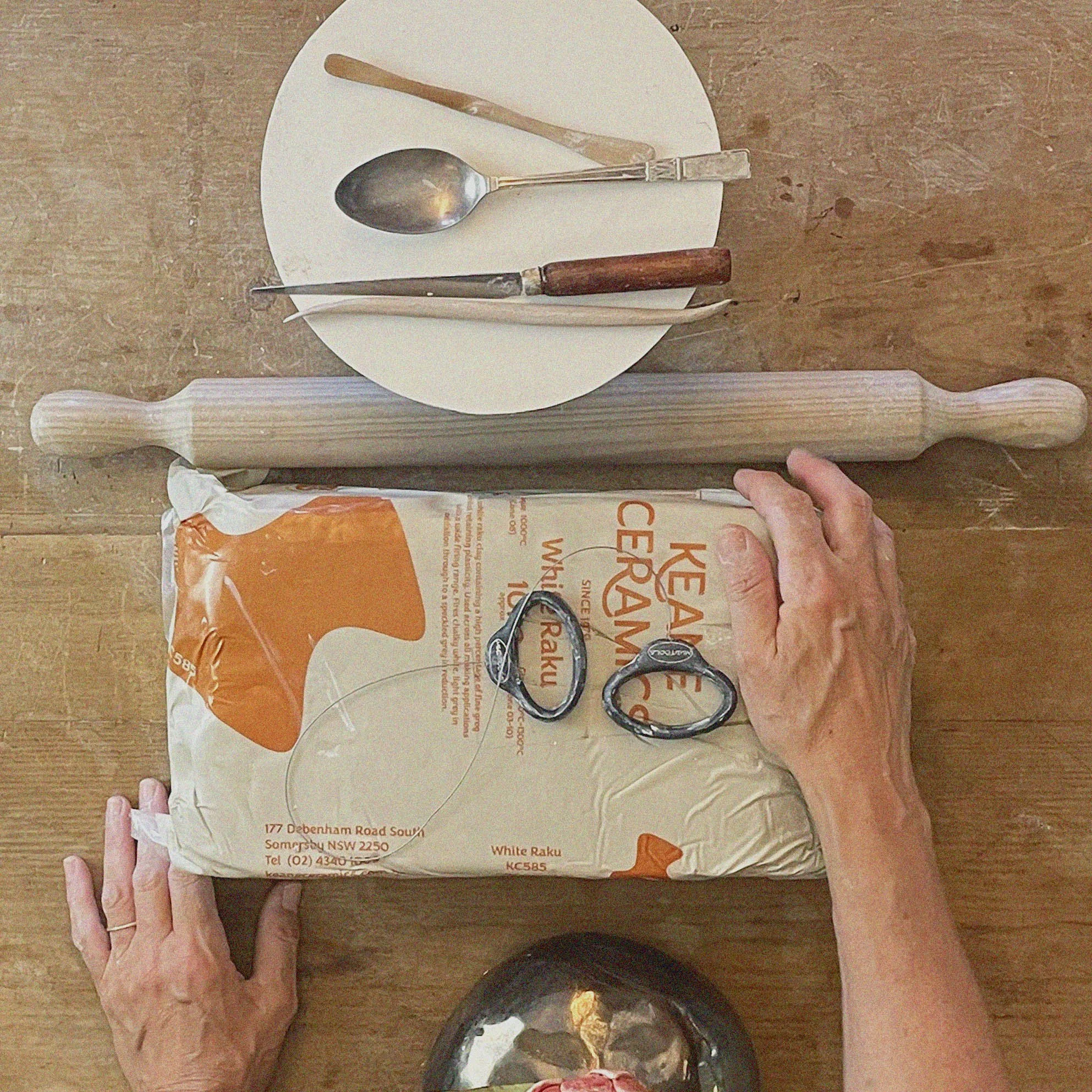 Rolling pin, bag of flour, kitchen utensils, and a pair of scissors on a wooden table.