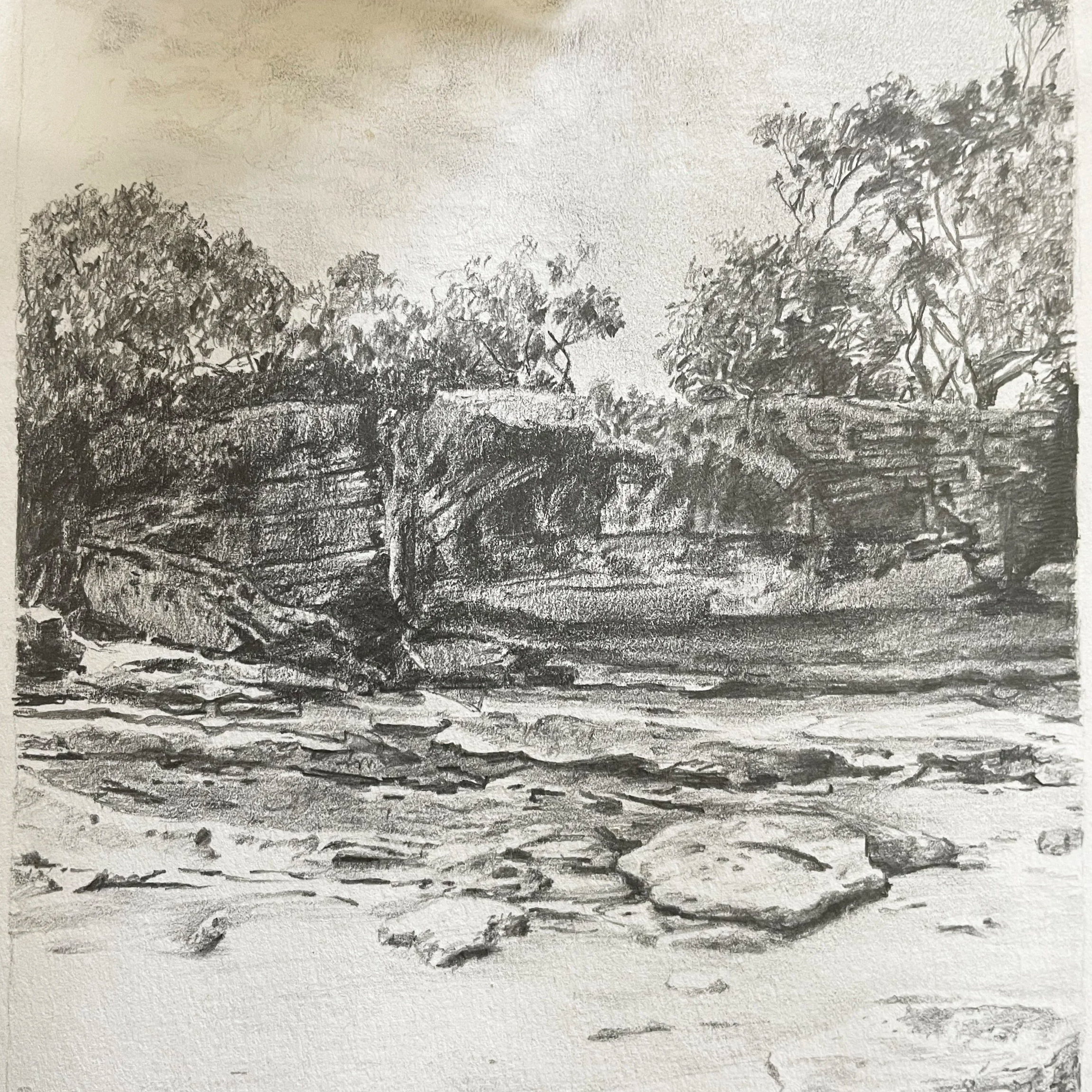 Black and white pencil sketch of a river landscape with rocks in the foreground, trees and rocks on the riverbank, and trees in the background.
