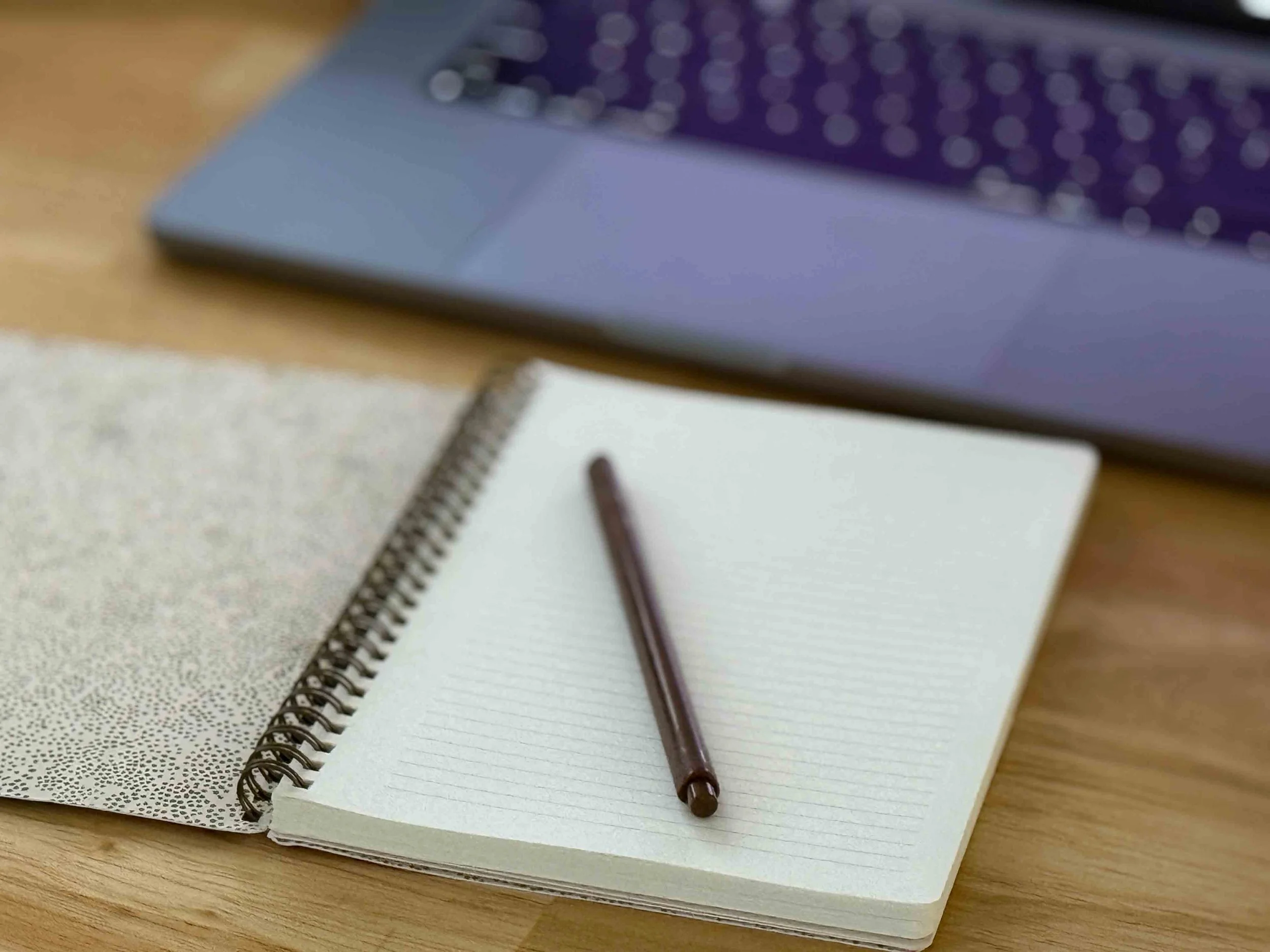An open notebook sits beside a laptop computer