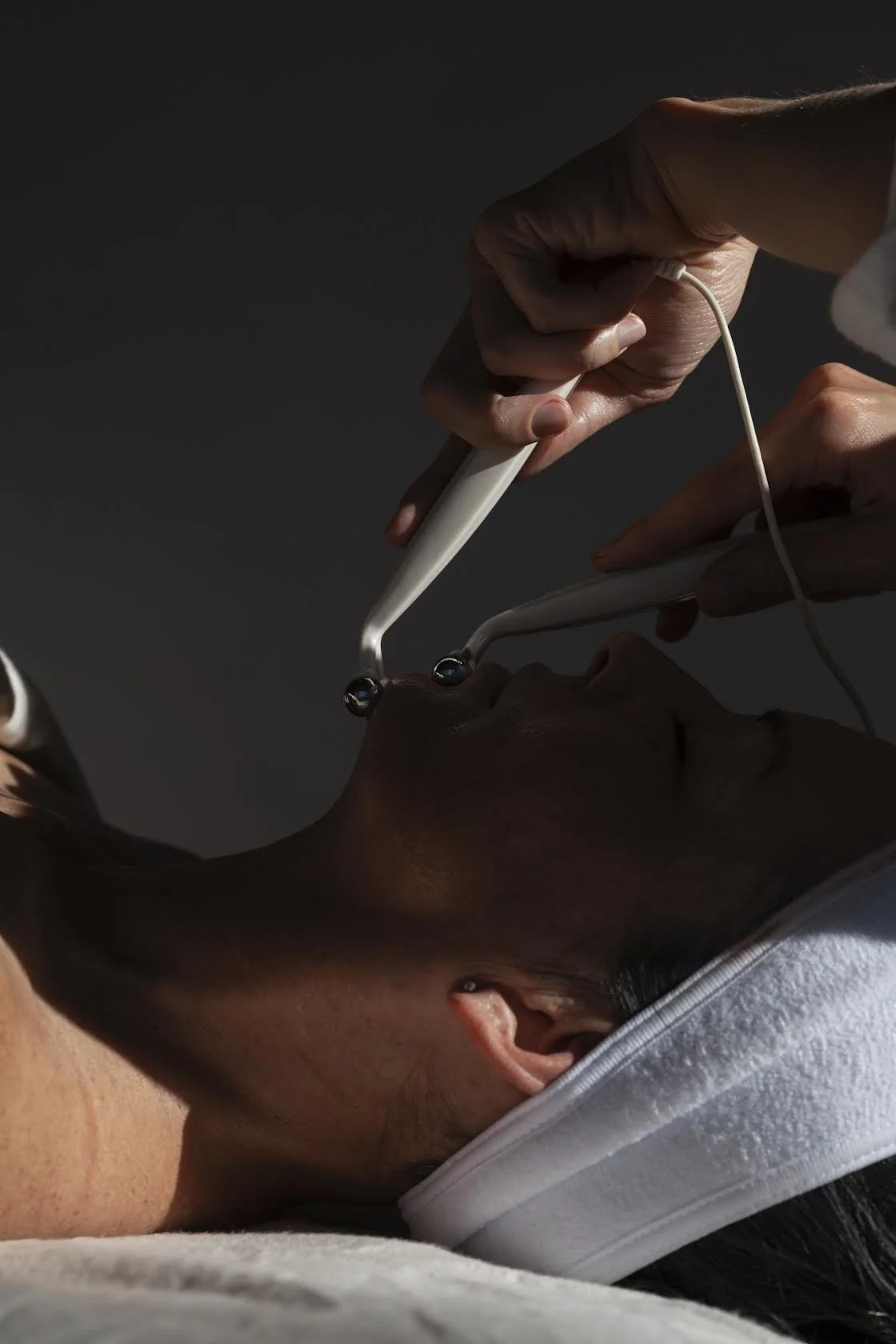 A person receiving a nasal swab test administered by a healthcare worker, with the patient lying down.