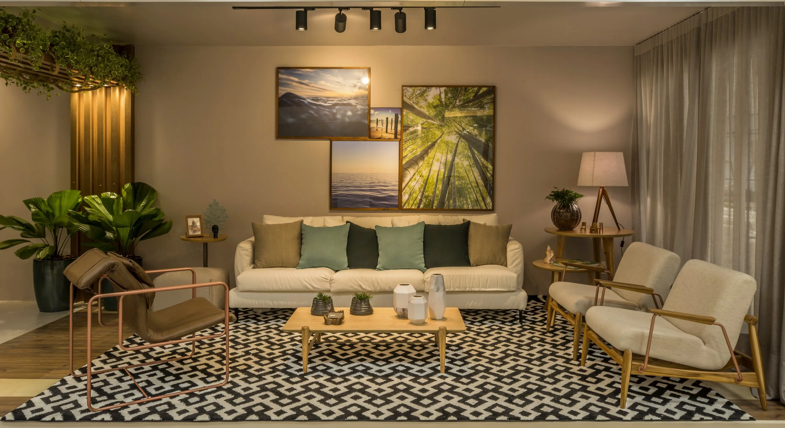 Living room with white sofa, beige armchairs, black-and-white geometric rug, and artwork featuring nature scenes on the wall.