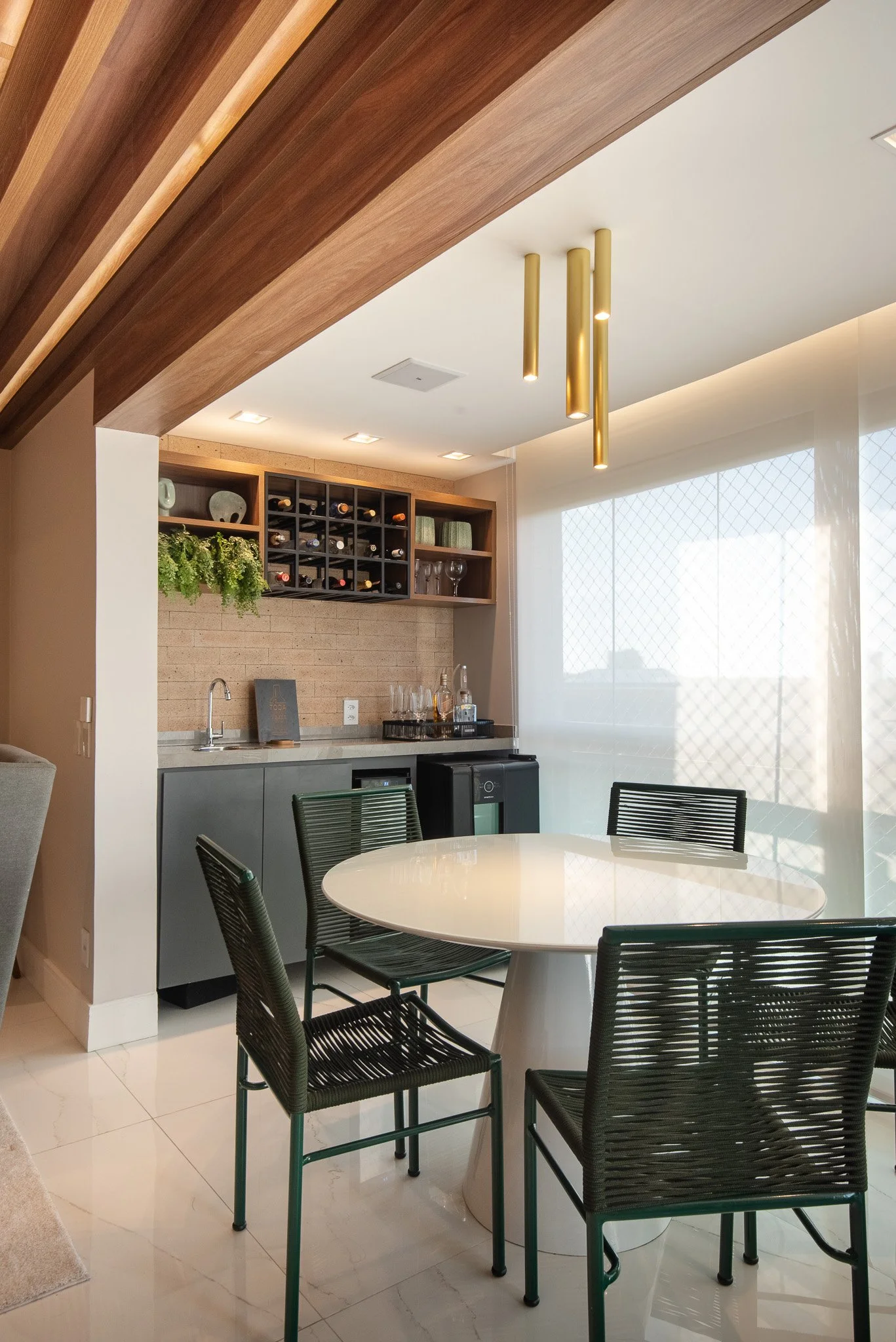 Modern kitchen and dining area with a round white table, six black chairs, a wine storage unit, floating shelves, glassware, and a large window