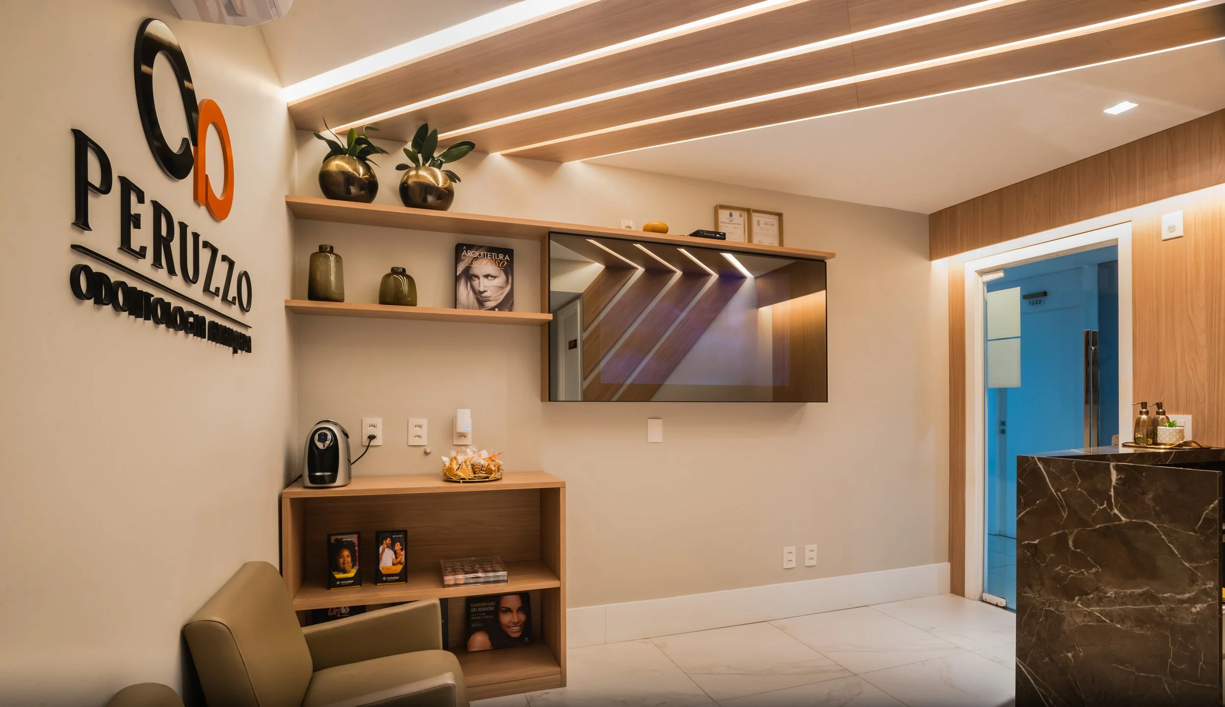 Reception area of Peruzlo optometry clinic with wall logo, decorative shelves, a large mirror, and a marble counter.