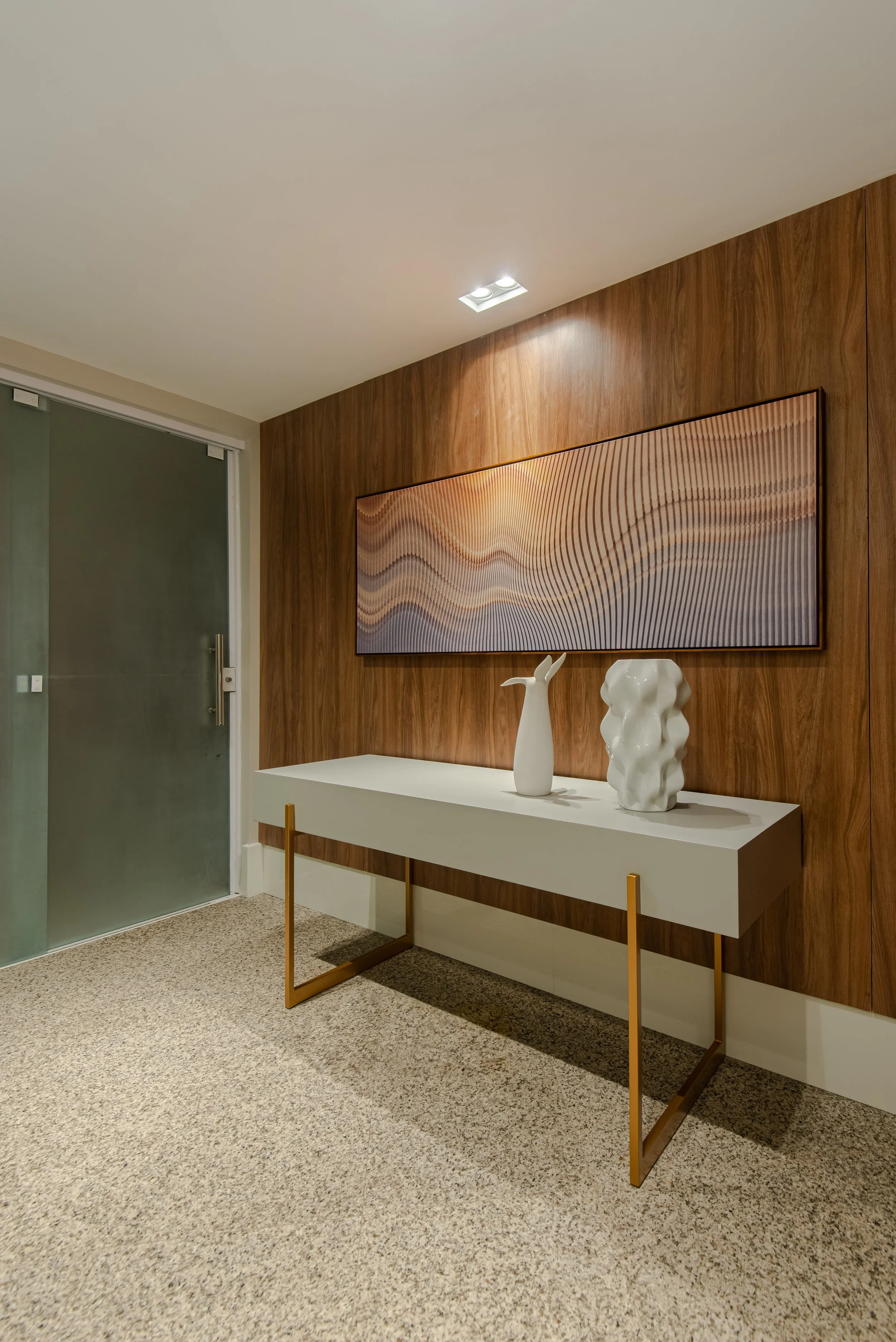 Modern interior with wooden accent wall, white sideboard, two white abstract ceramic sculptures, and an elongated abstract wall art piece