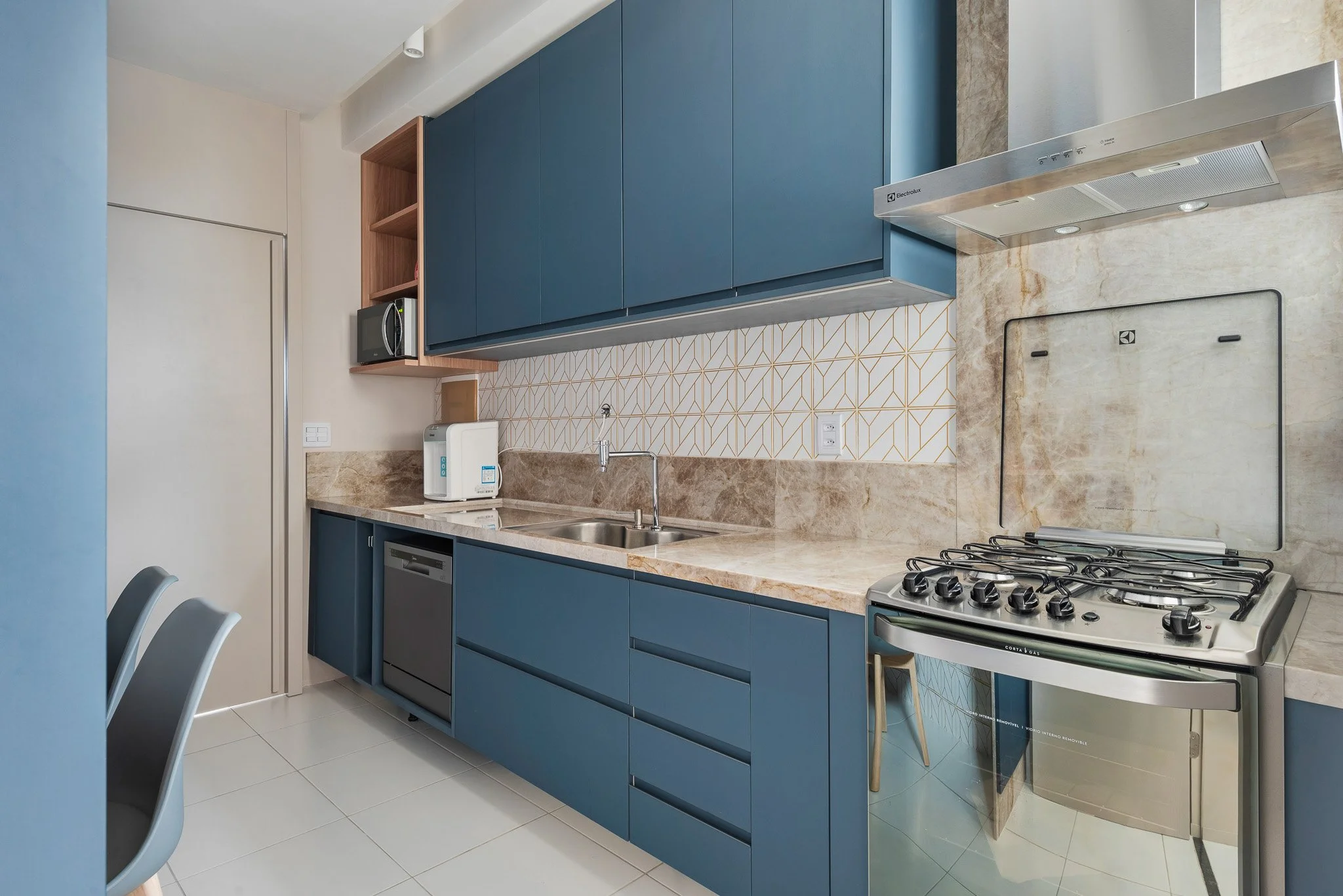 Modern kitchen with blue cabinets, beige marble countertops, a stainless steel stove, stainless steel dishwasher, and small appliances including a microwave and water purifier.