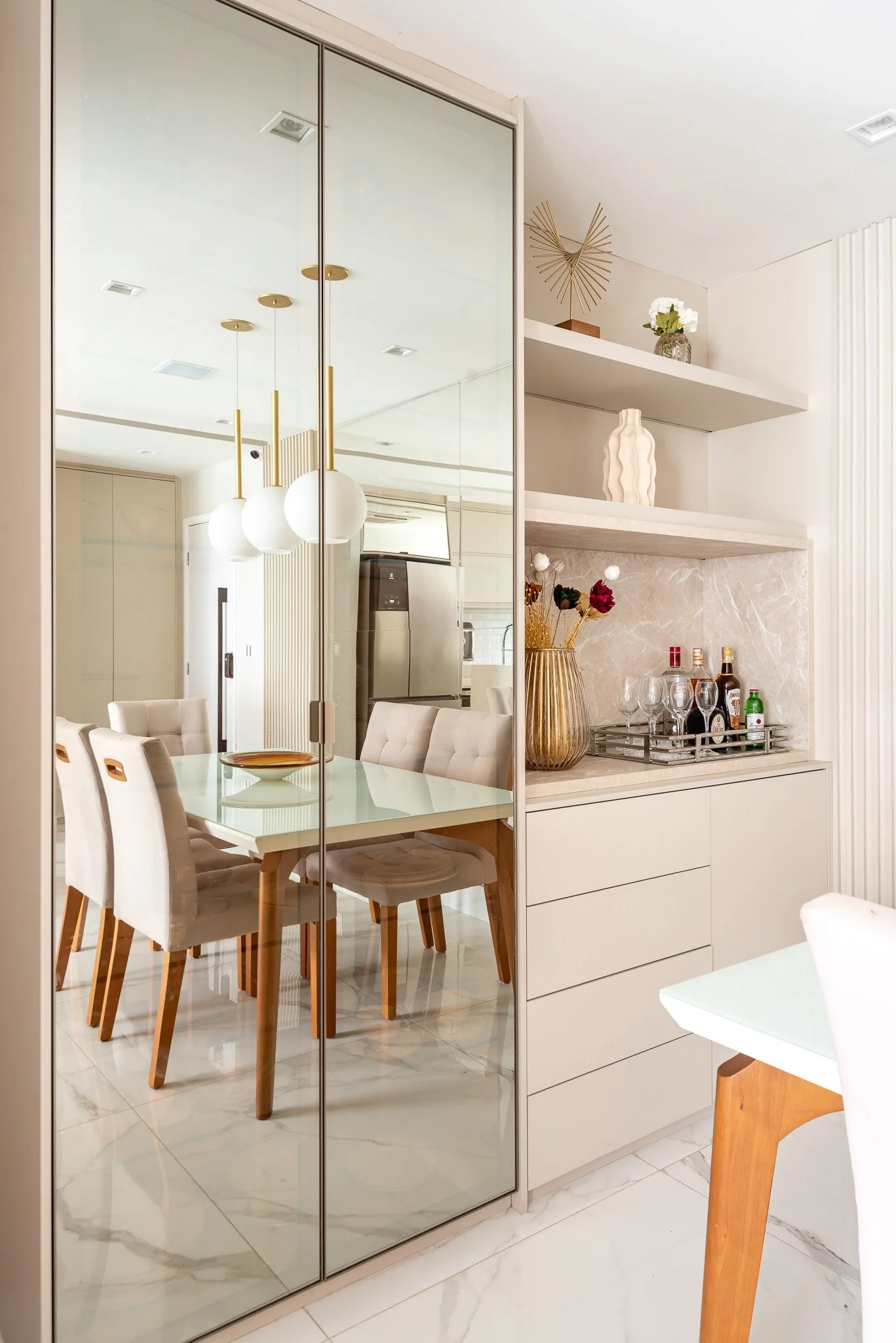 Interior view of a dining area with glass sliding doors, white and beige furniture, artwork, and decorative items.