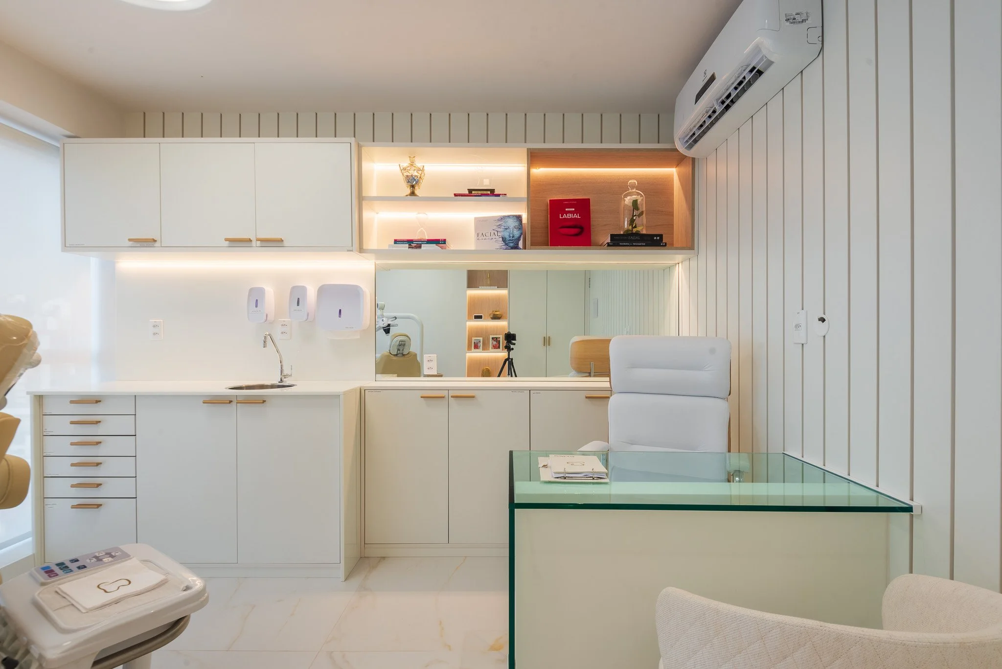 Medical or dental office with cabinets, a mirror, white air conditioning unit, glass desk, and medical supplies.