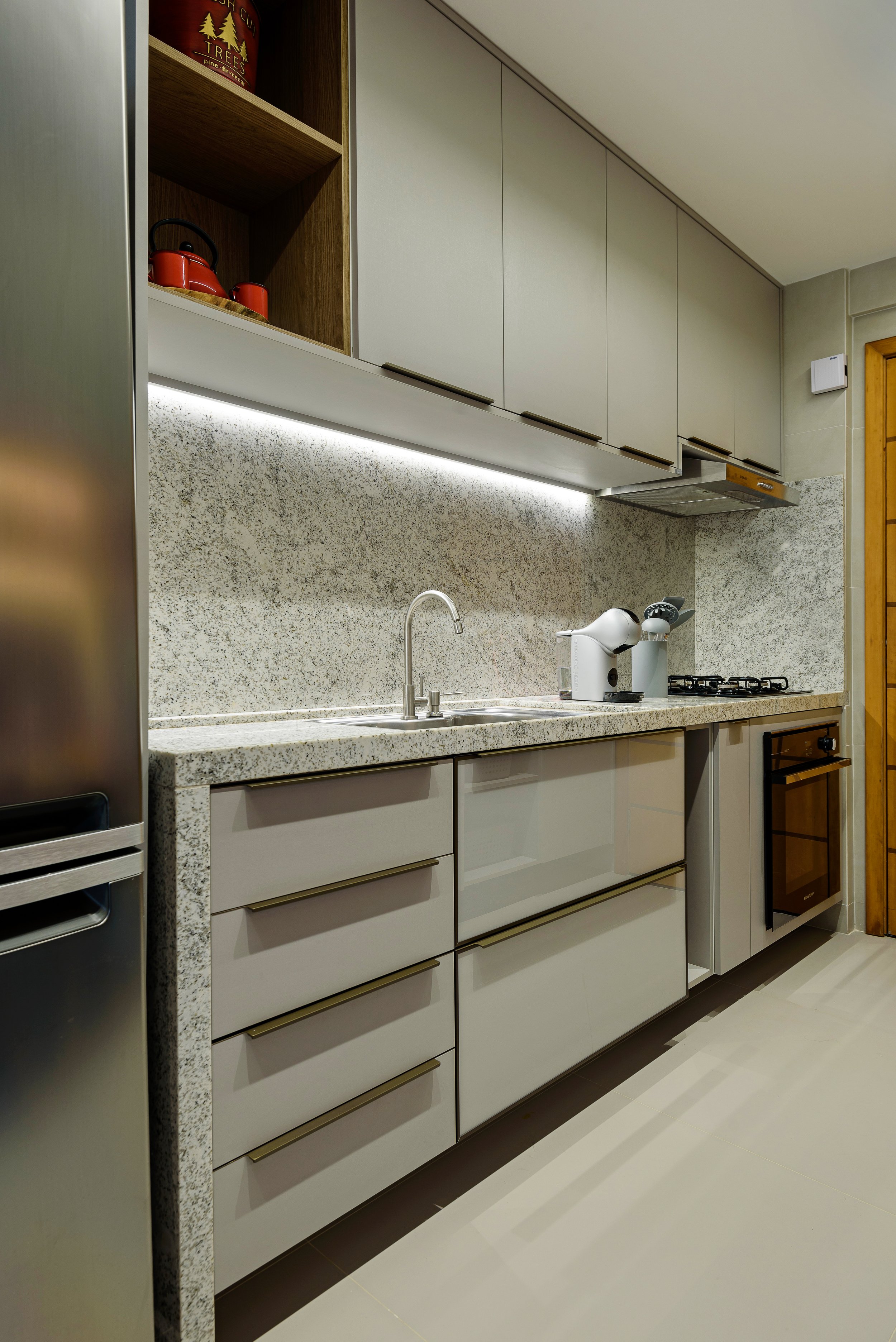 Modern kitchen with gray cabinets, granite countertop, and backsplash, with kitchen appliances including a red kettle and a coffee machine.