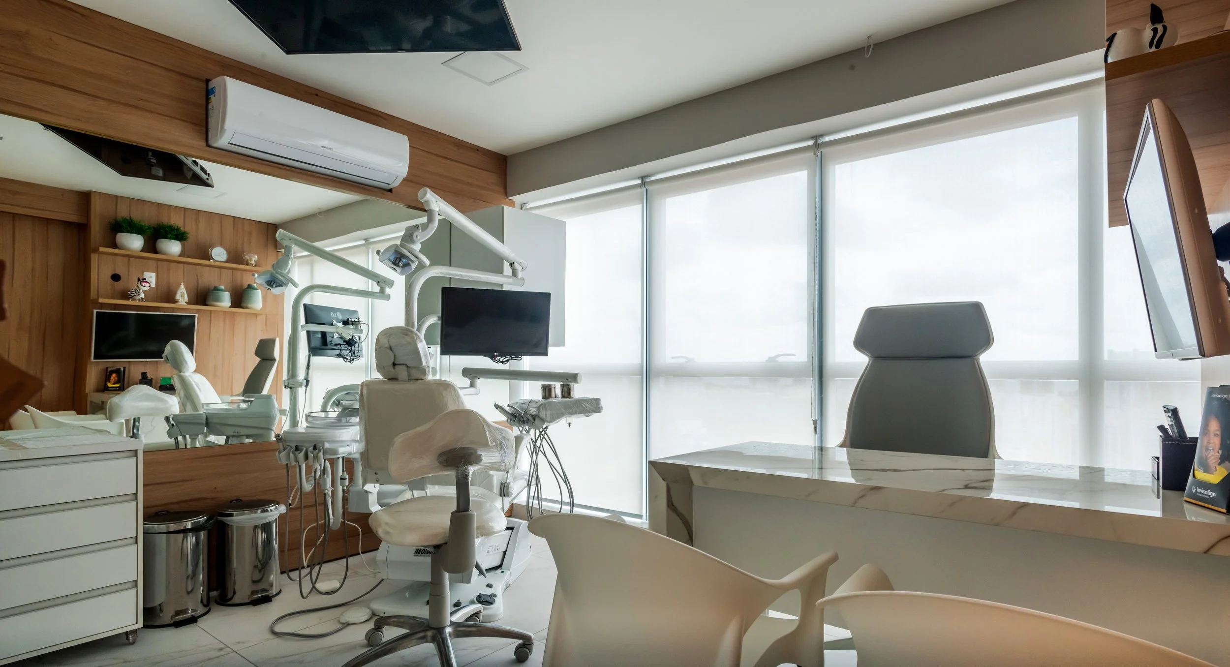 Modern dental clinic interior with dental chair, monitor, and dental equipment near large windows with blinds