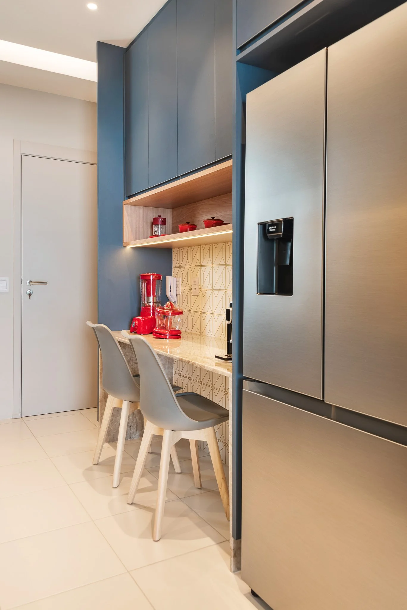 Modern kitchen with blue cabinets, red appliances, and a stainless steel refrigerator.