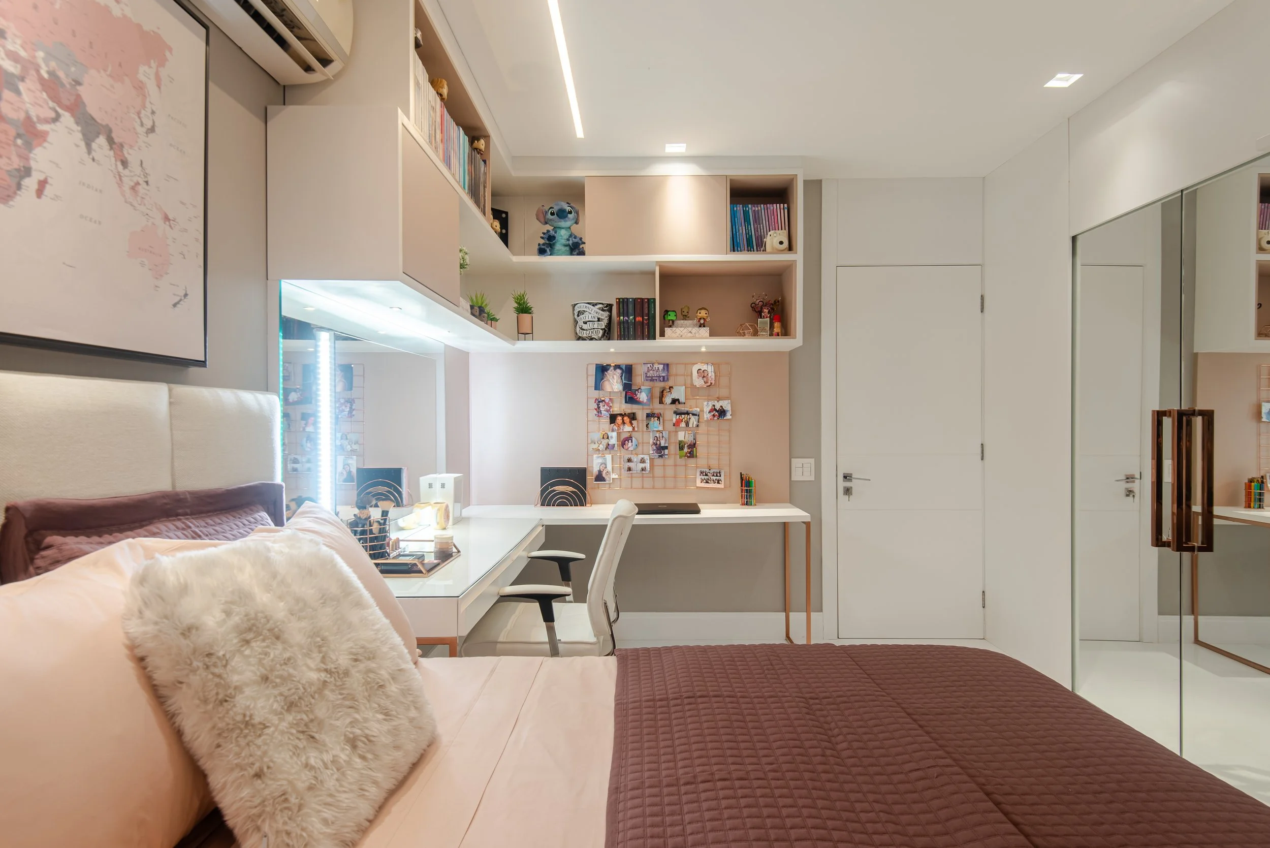 A bedroom with a bed, desk, shelves, and closet, decorated with books, photos, figurines, and plants.