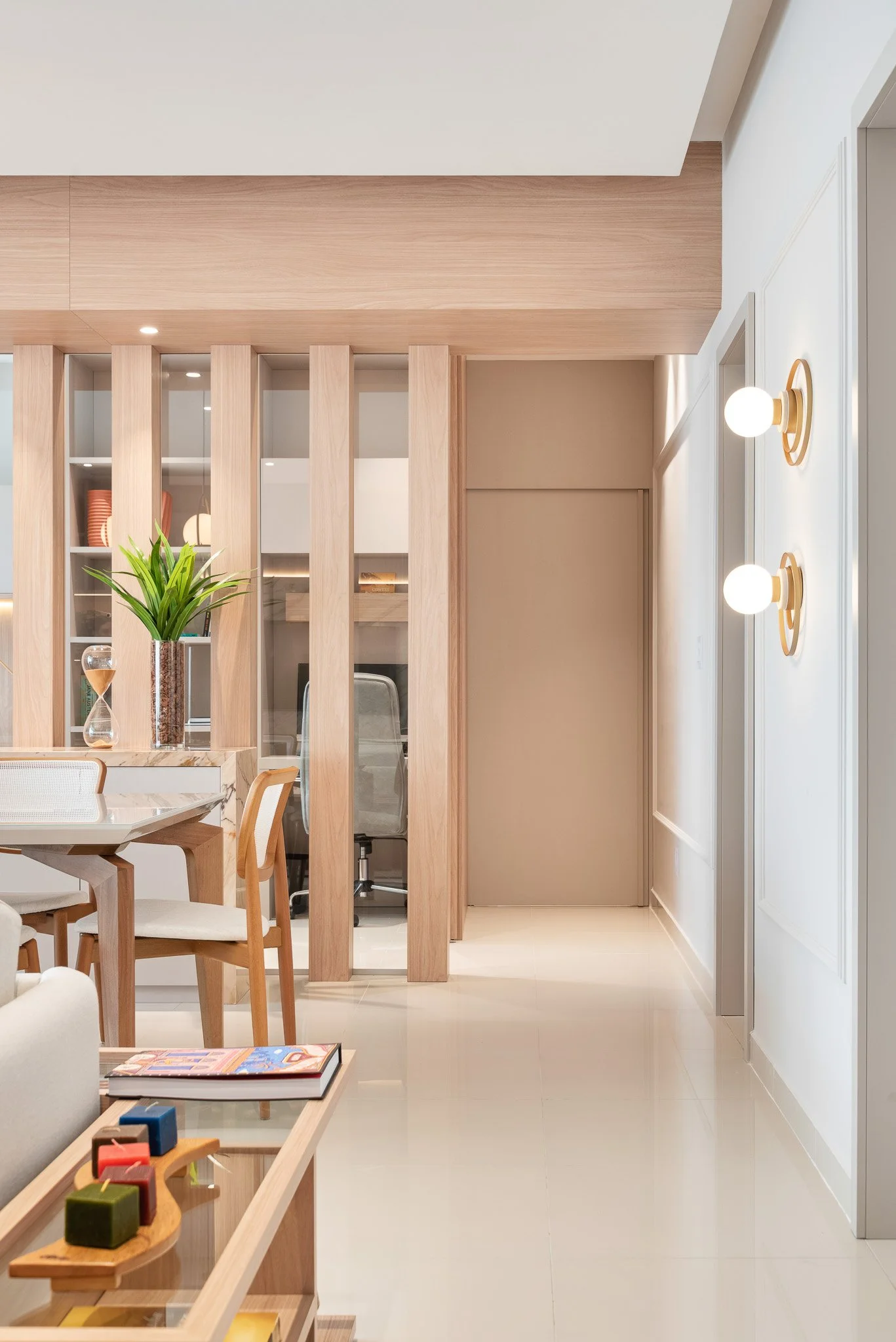 Modern interior living space with wooden accents, a glass partition, and decorative lighting fixtures.