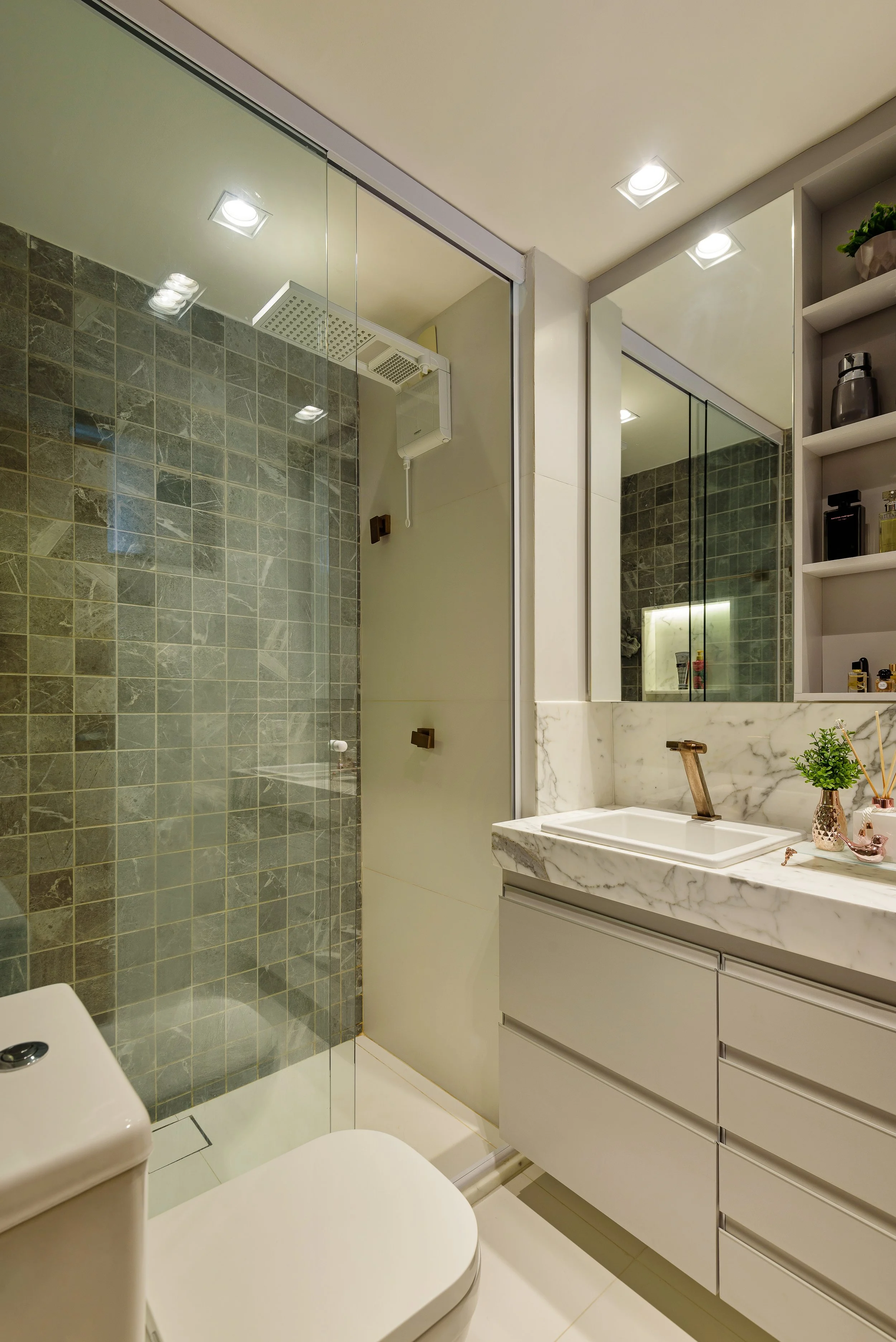 Modern bathroom with a glass shower enclosure, white vanity with marble countertop, mirror, and shelves with decorative items and toiletries.