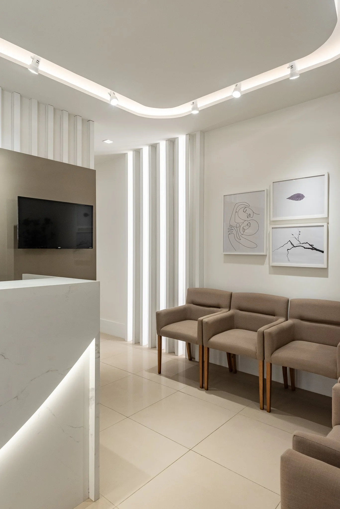 Modern waiting room with beige chairs, white walls, and abstract artwork hanging on the wall.