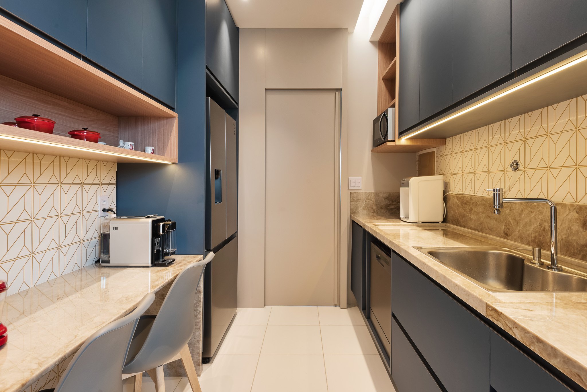 Modern kitchen with blue and wood cabinets, marble countertops, stainless steel appliances, and patterned backsplash.