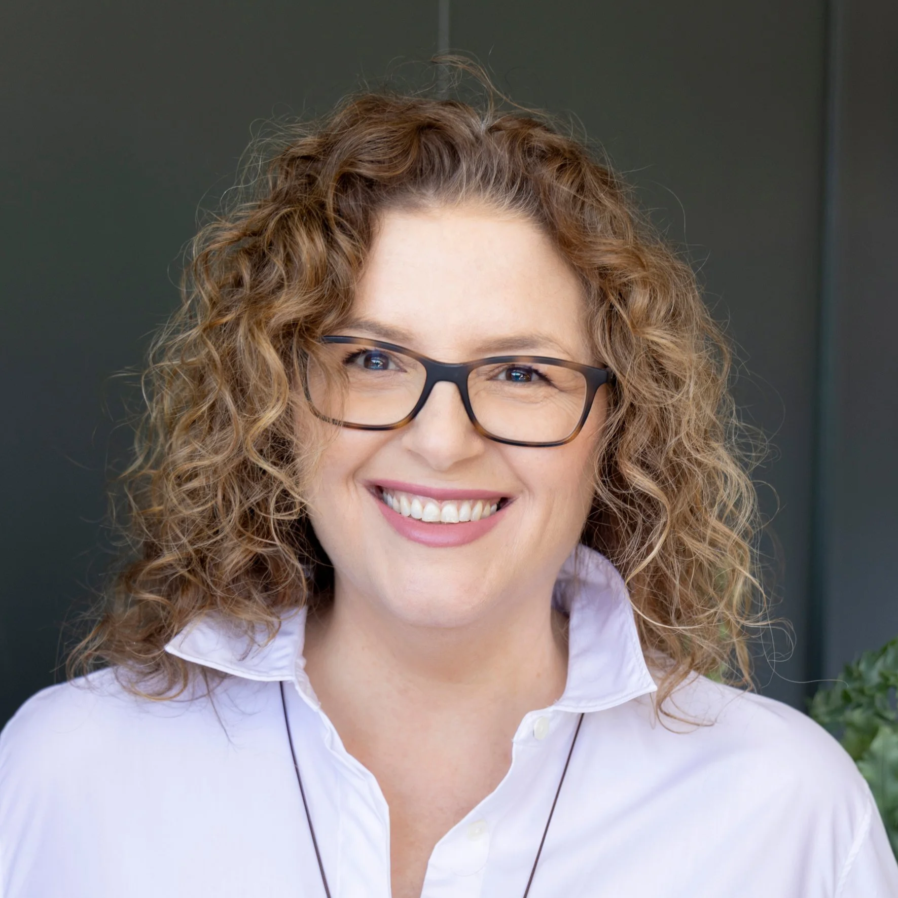Lee Sailsbury, Pool Industry expert - Business mentor and coach . A woman with curly red hair wearing glasses and a white collared shirt, smiling in an indoor setting.