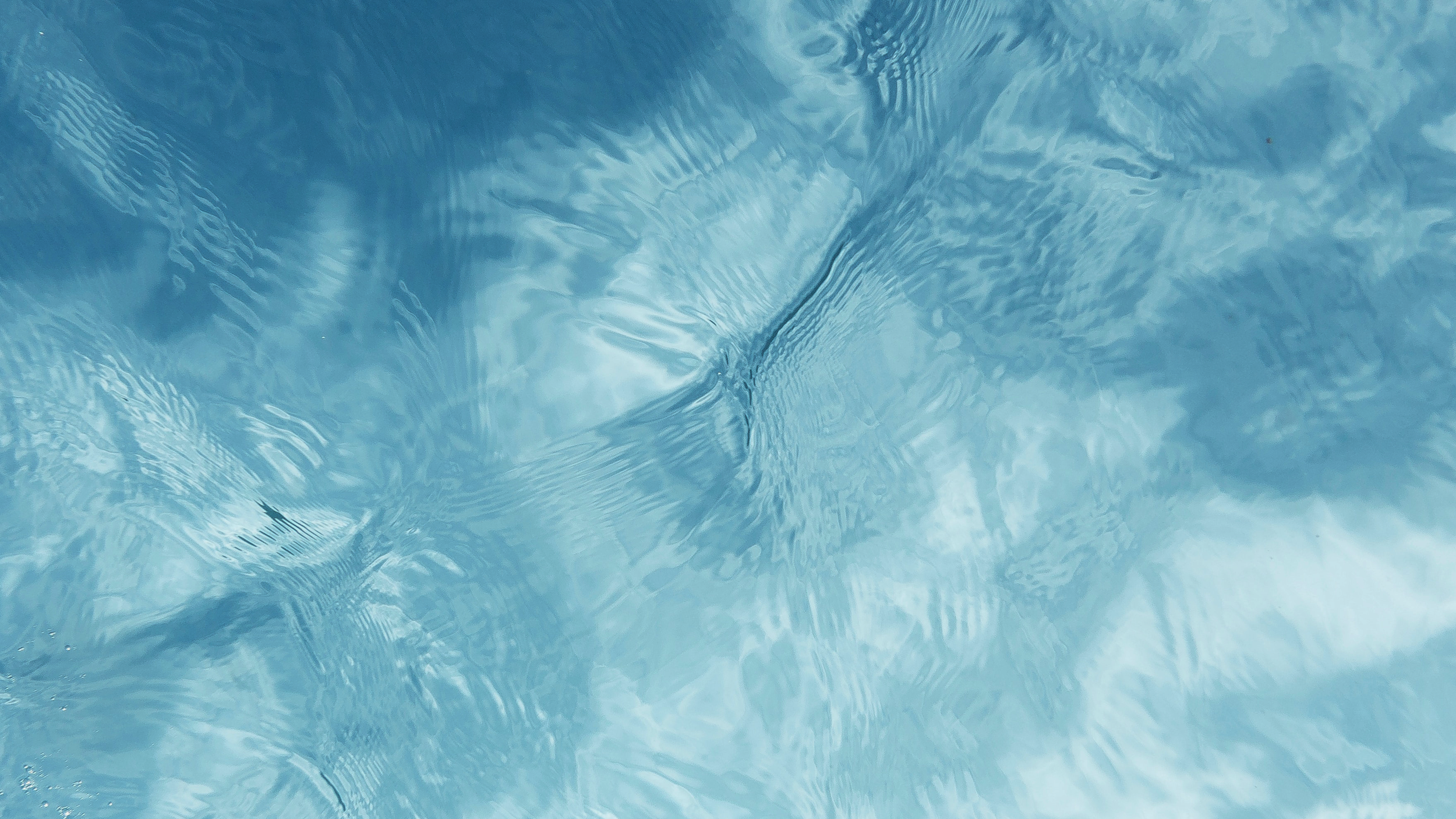 Close-up of clear blue water with ripples and reflections.