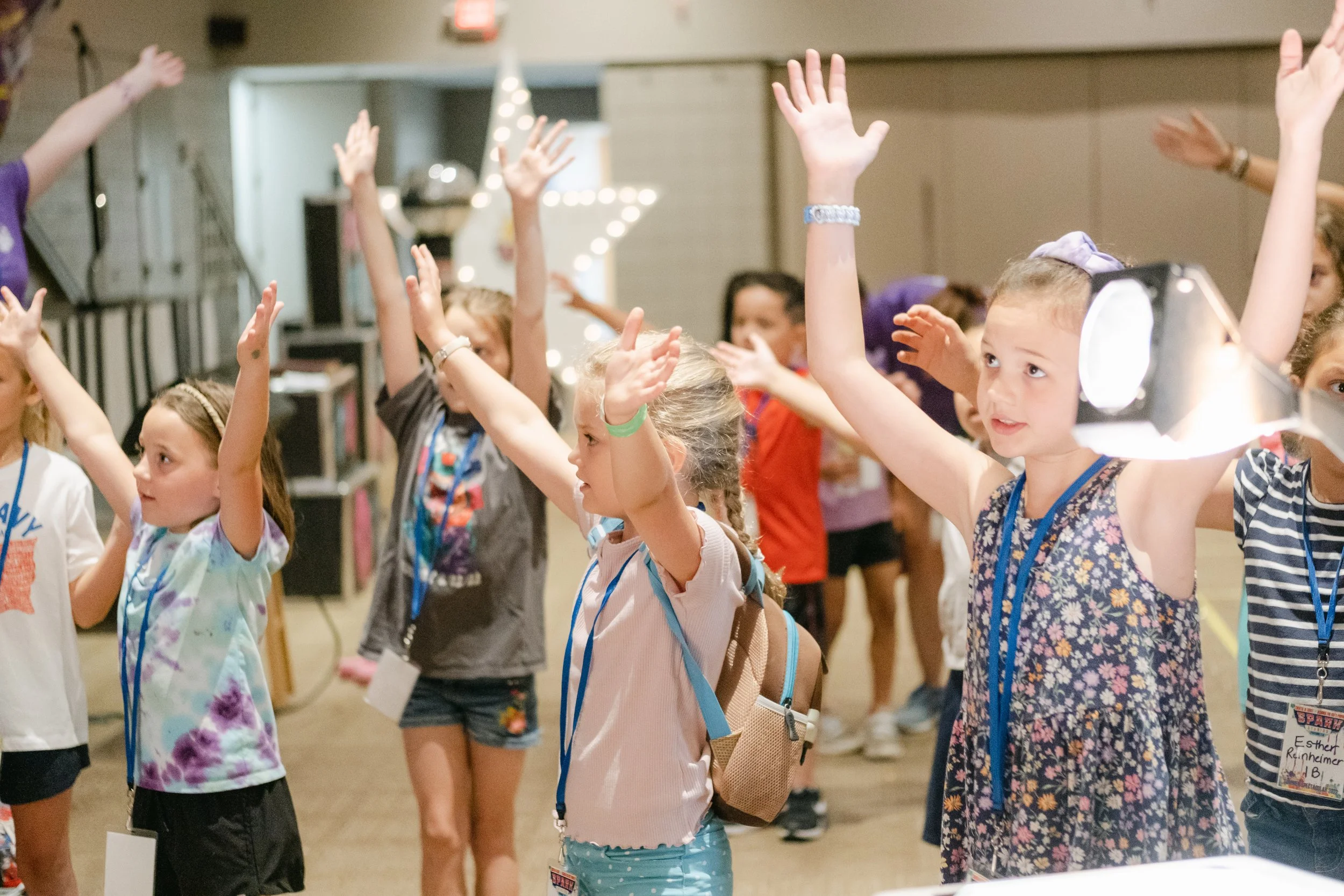 Group of young children raising their hands during a classroom activity