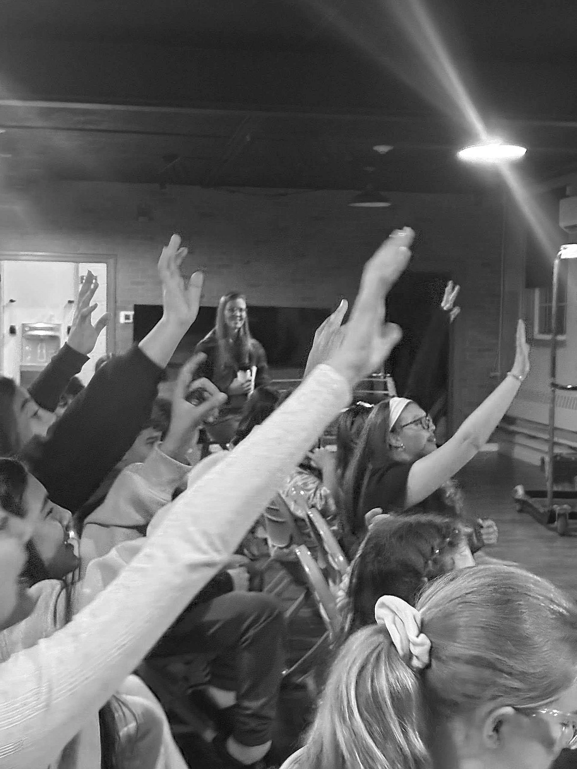 students raising their hands to participate in youth group discipleship hour
