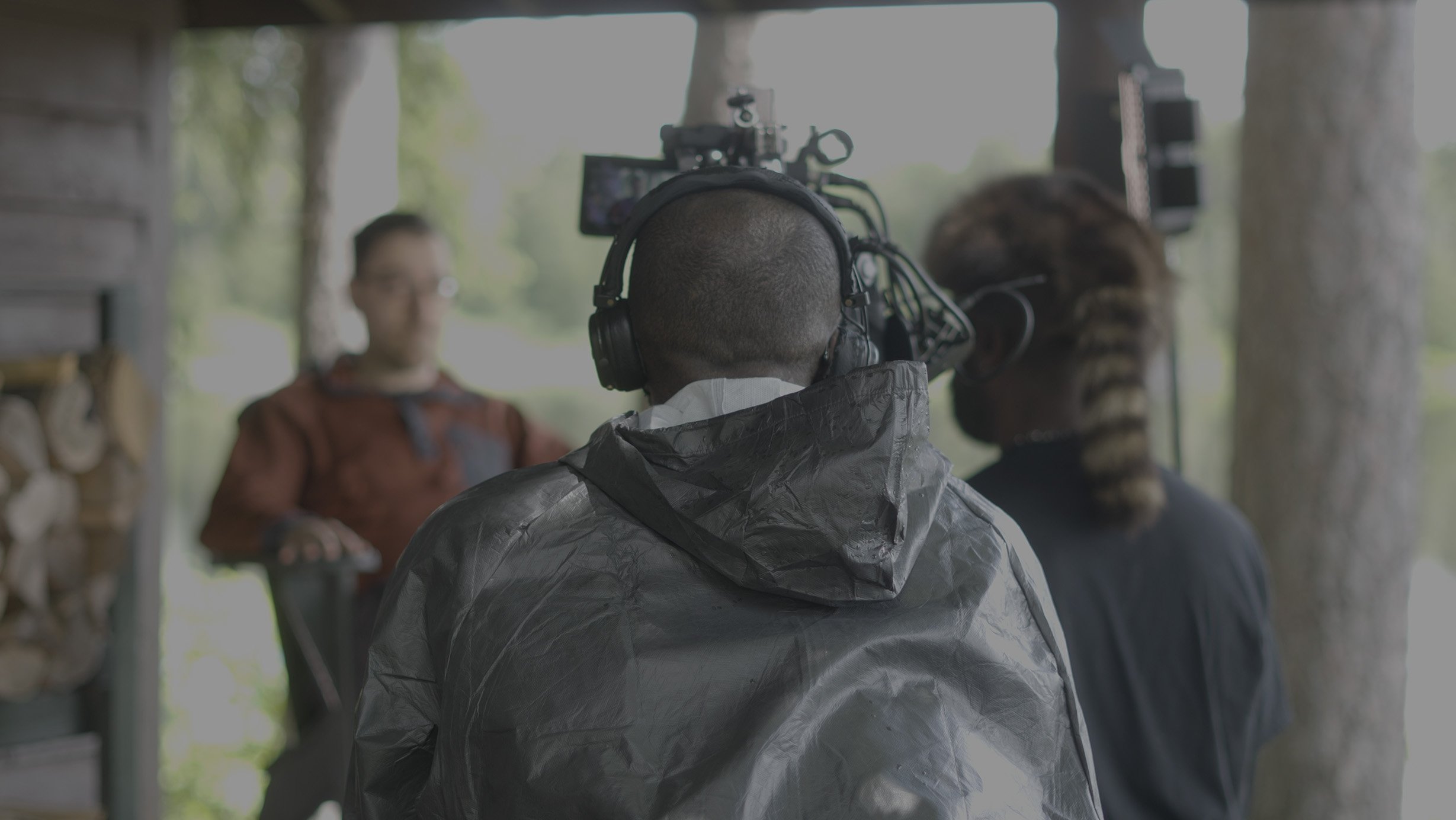 Behind-the-scenes of a film or video shoot with a cameraman filming two people in an outdoor setting.