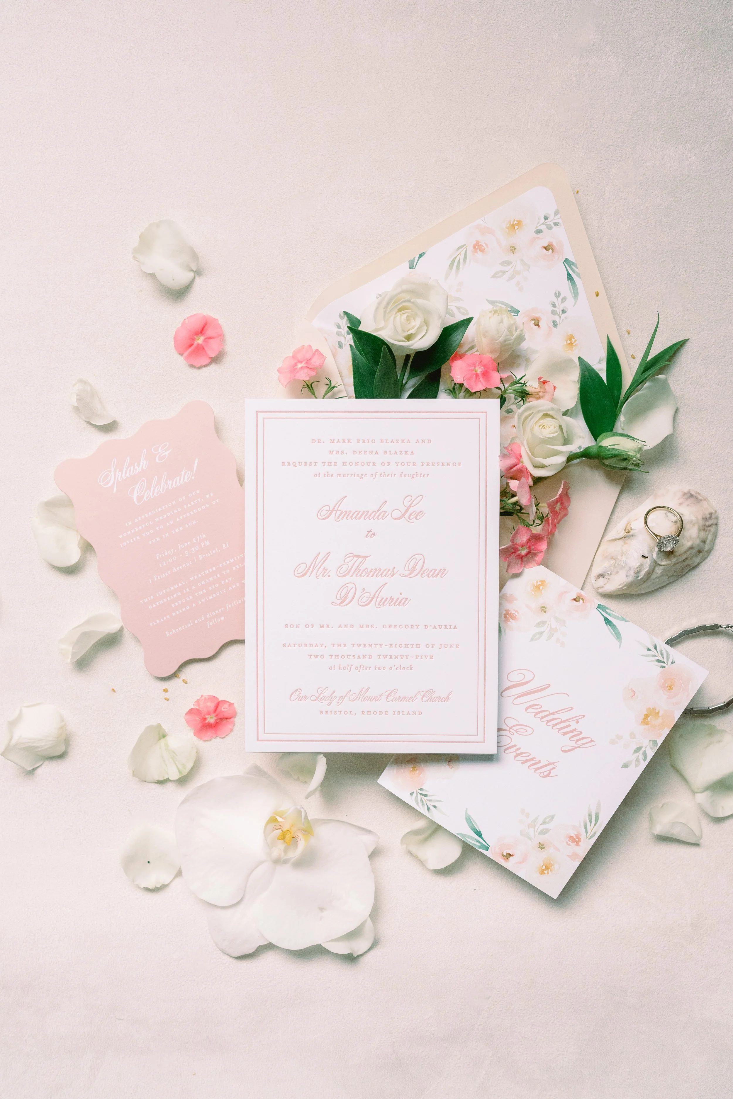 Wedding invitation, RSVP card, floral decor, wedding ring, and flowers on a white surface