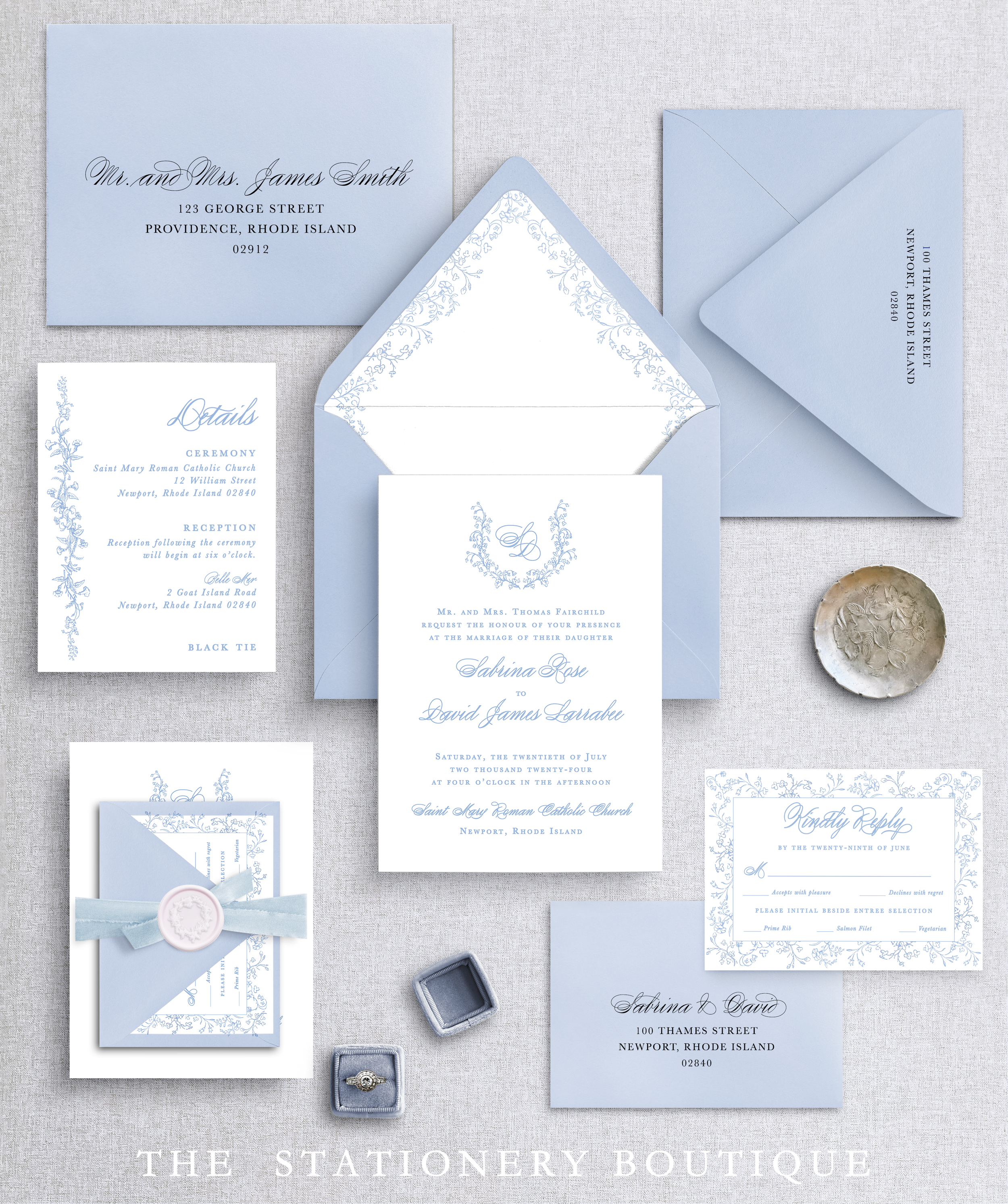 Light blue wedding invitation suite including envelopes, RSVP card, details card, a small box with a ring, and decorative elements.