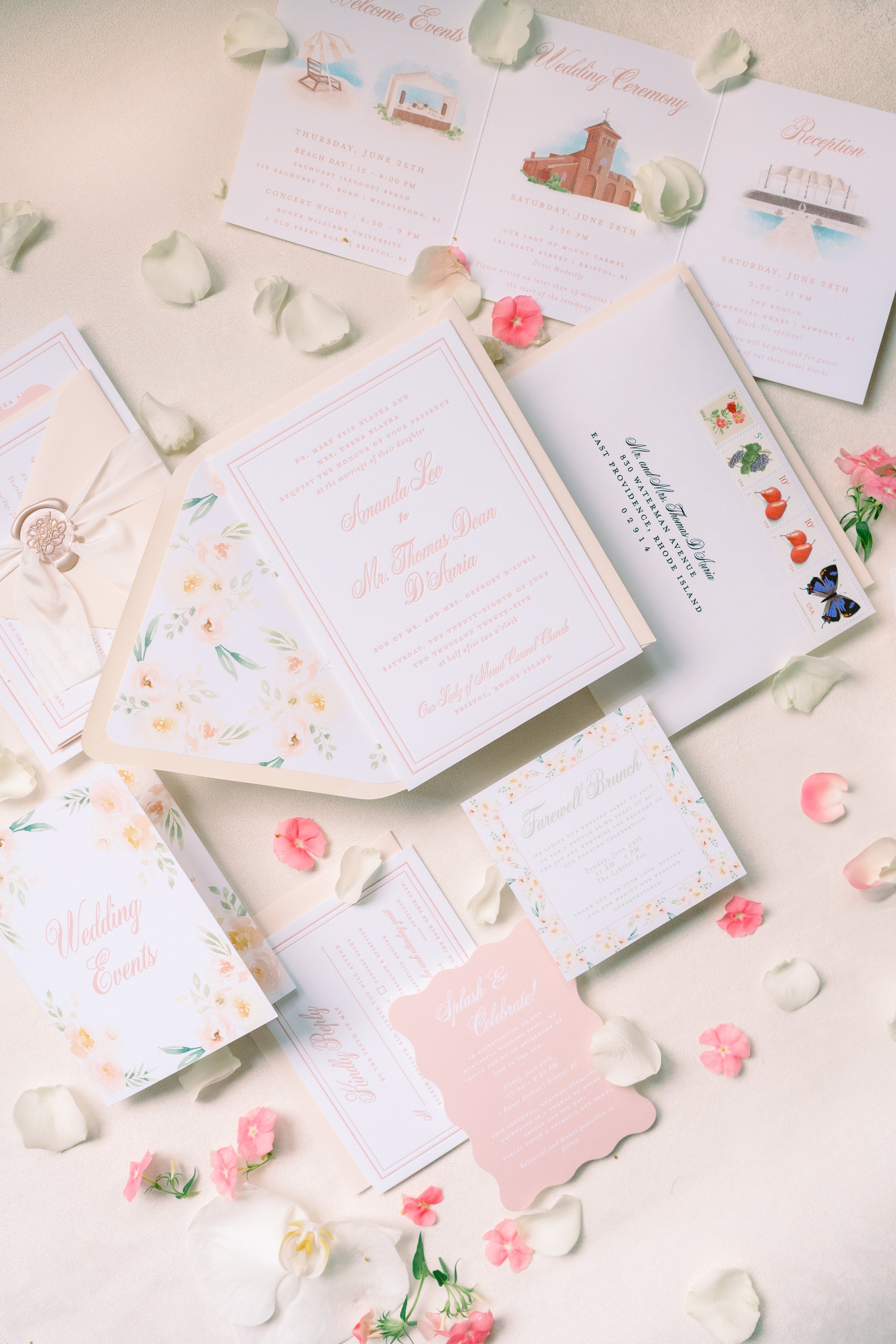 Wedding invitations, programs, and small cards arranged on a light surface, decorated with scattered white and pink flower petals.