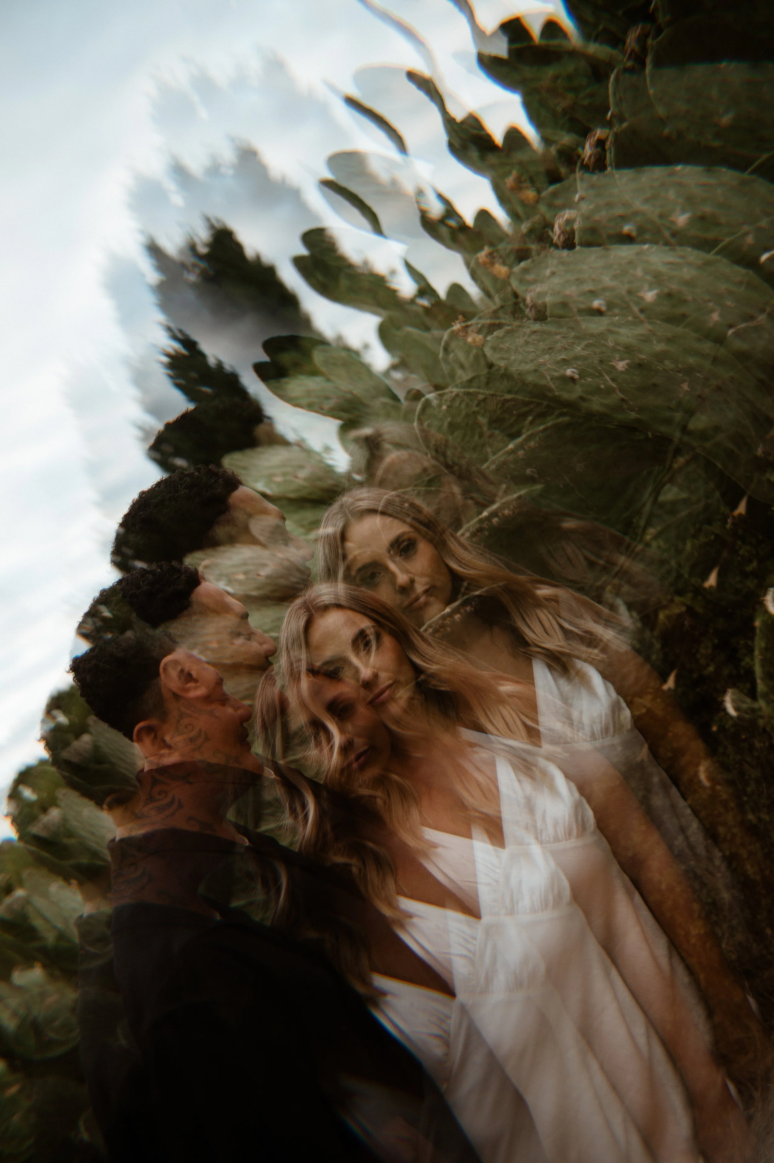 Multiple overlapping images of a woman with long blonde hair in a white dress, a man with tattoos and a dark shirt, and cactus plants in the background, creating a layered, abstract photo.