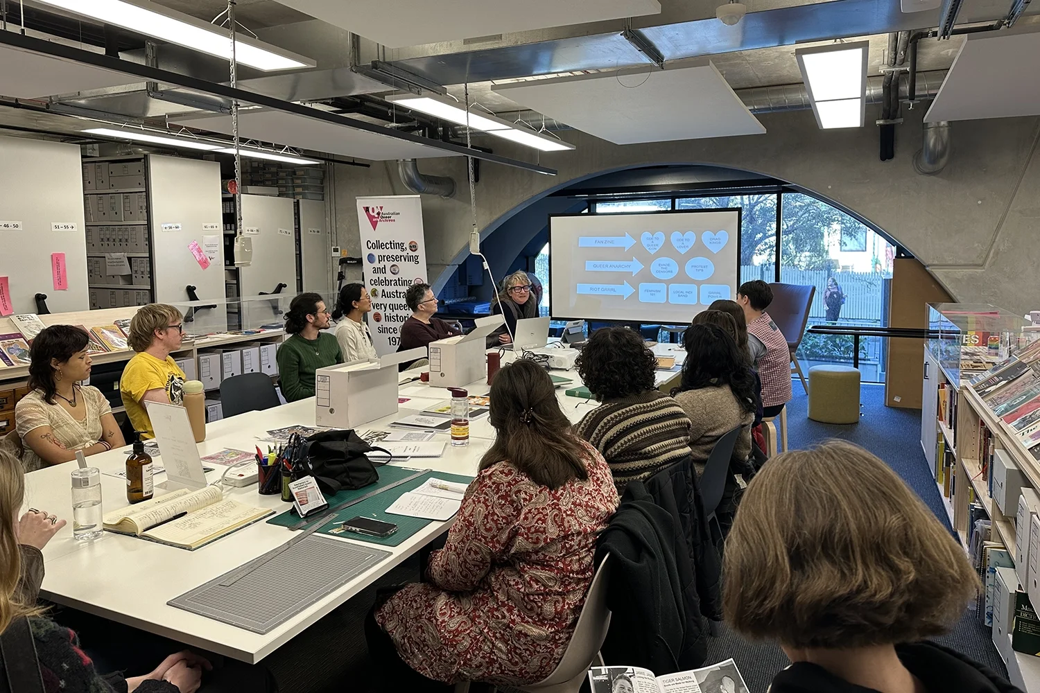 People gathered around a table with zine-making materials in the Australian Queer Archive