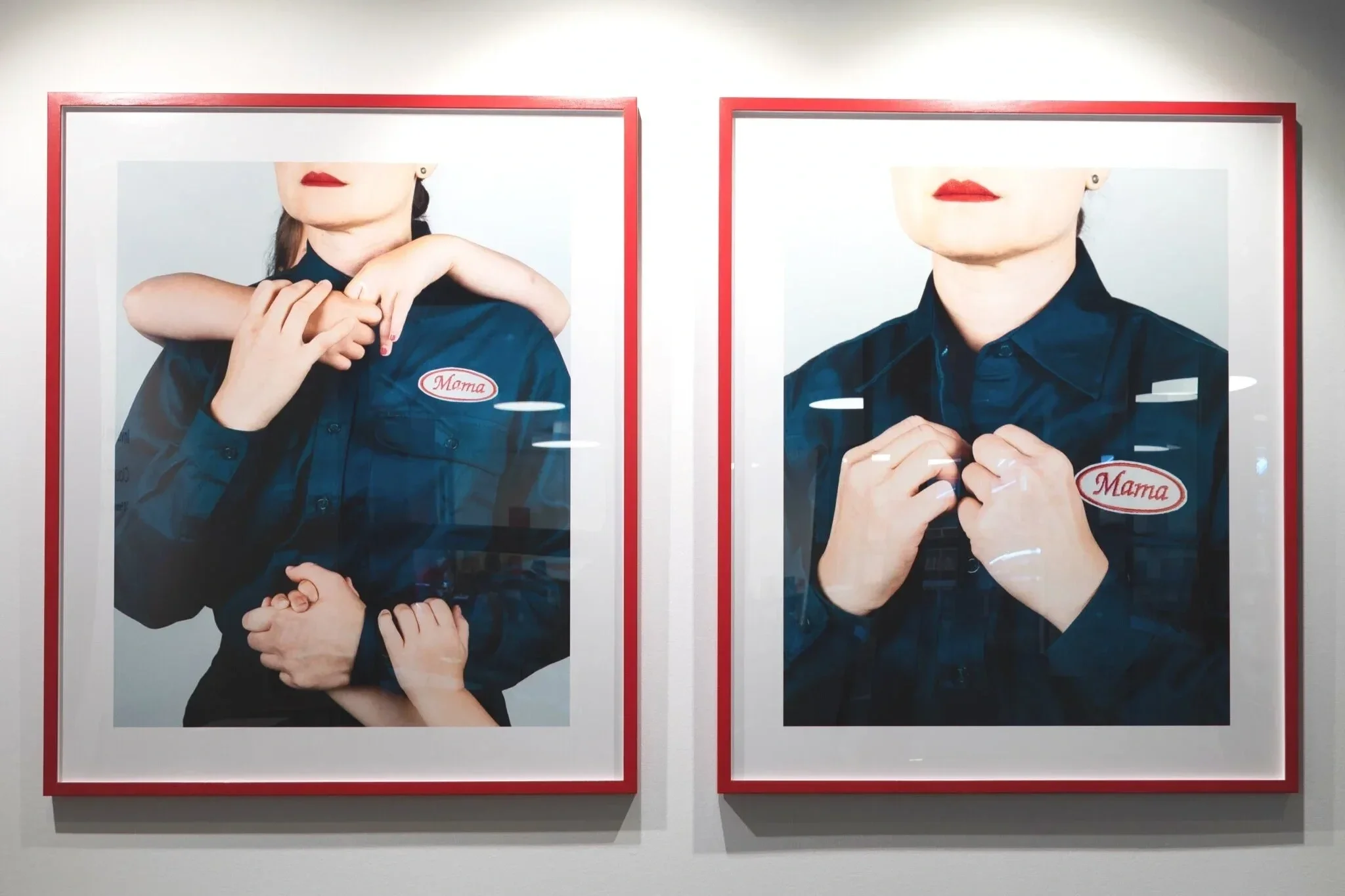 Two red-framed photographs on a gallery wall showing images of a mother