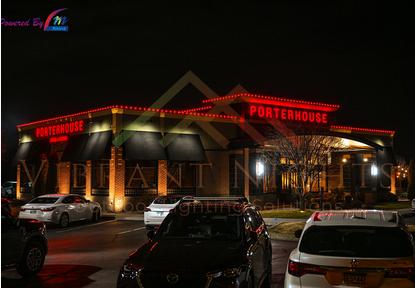 Exterior of a Port House restaurant at night with cars parked in front, illuminated red and yellow signage, and trees nearby.