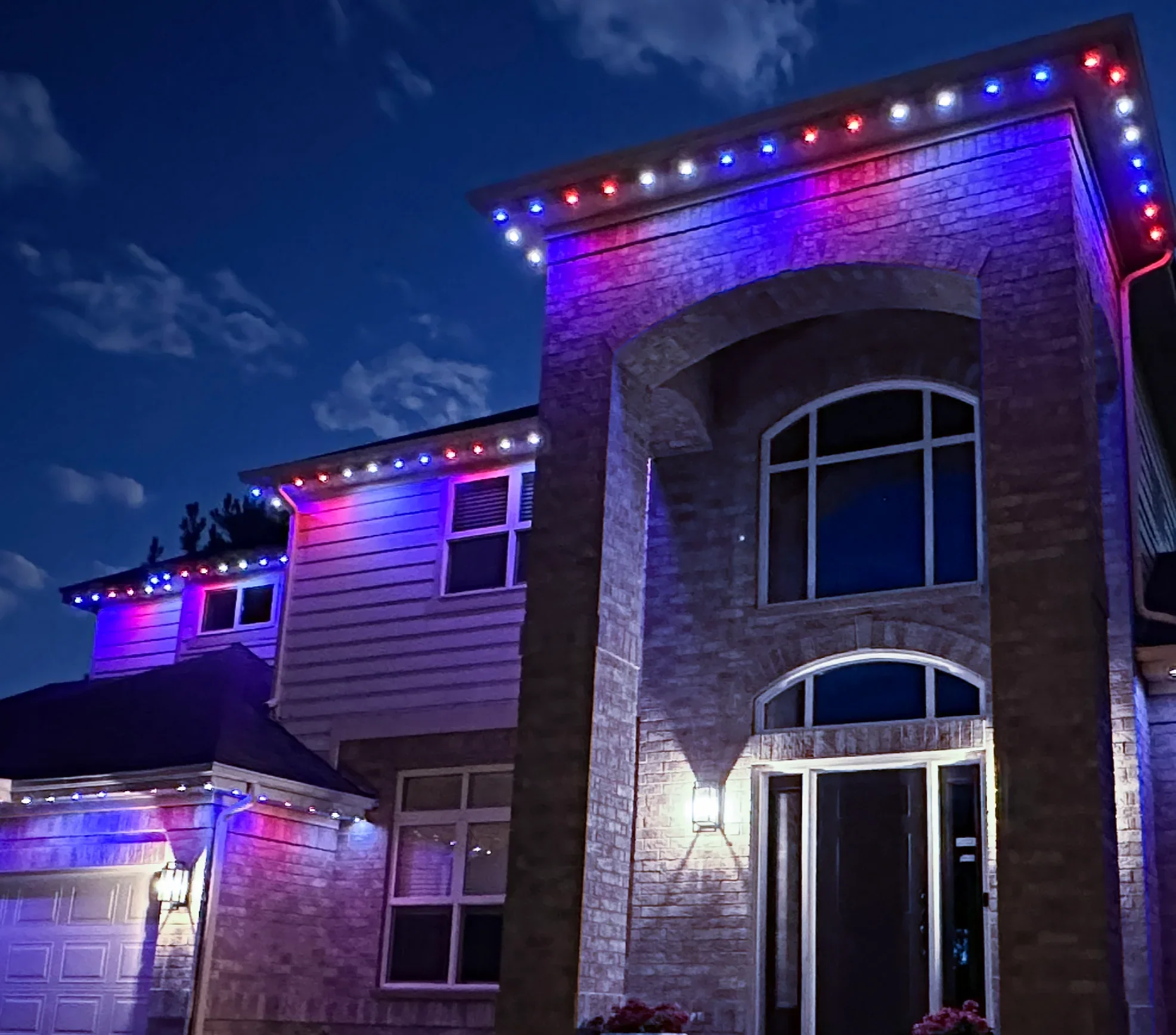 A house decorated with string lights in red, white, and blue colors at night.