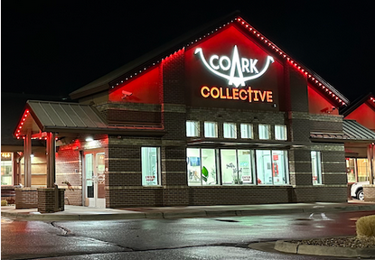 Night view of a building with a sign that reads 'COARK COLLECTIVE' illuminated in red and white lights.