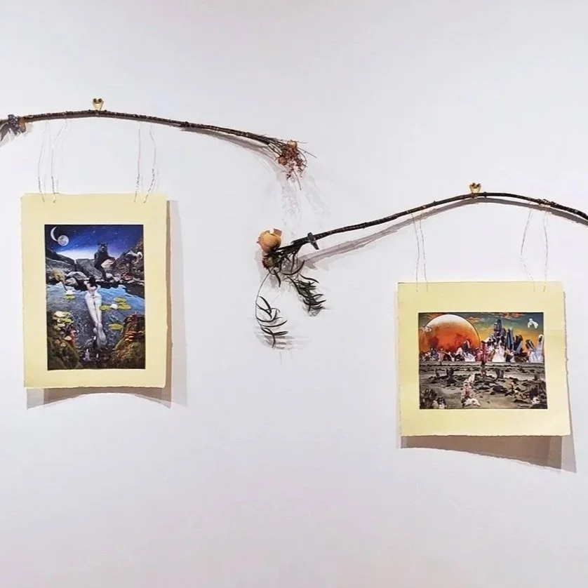 Two pictures hanging on a white wall, supported by small branches with additional natural decorations. The left picture depicts a person standing in a surreal landscape with celestial elements, while the right picture shows a futuristic scene with a large orange planet and city ruins.