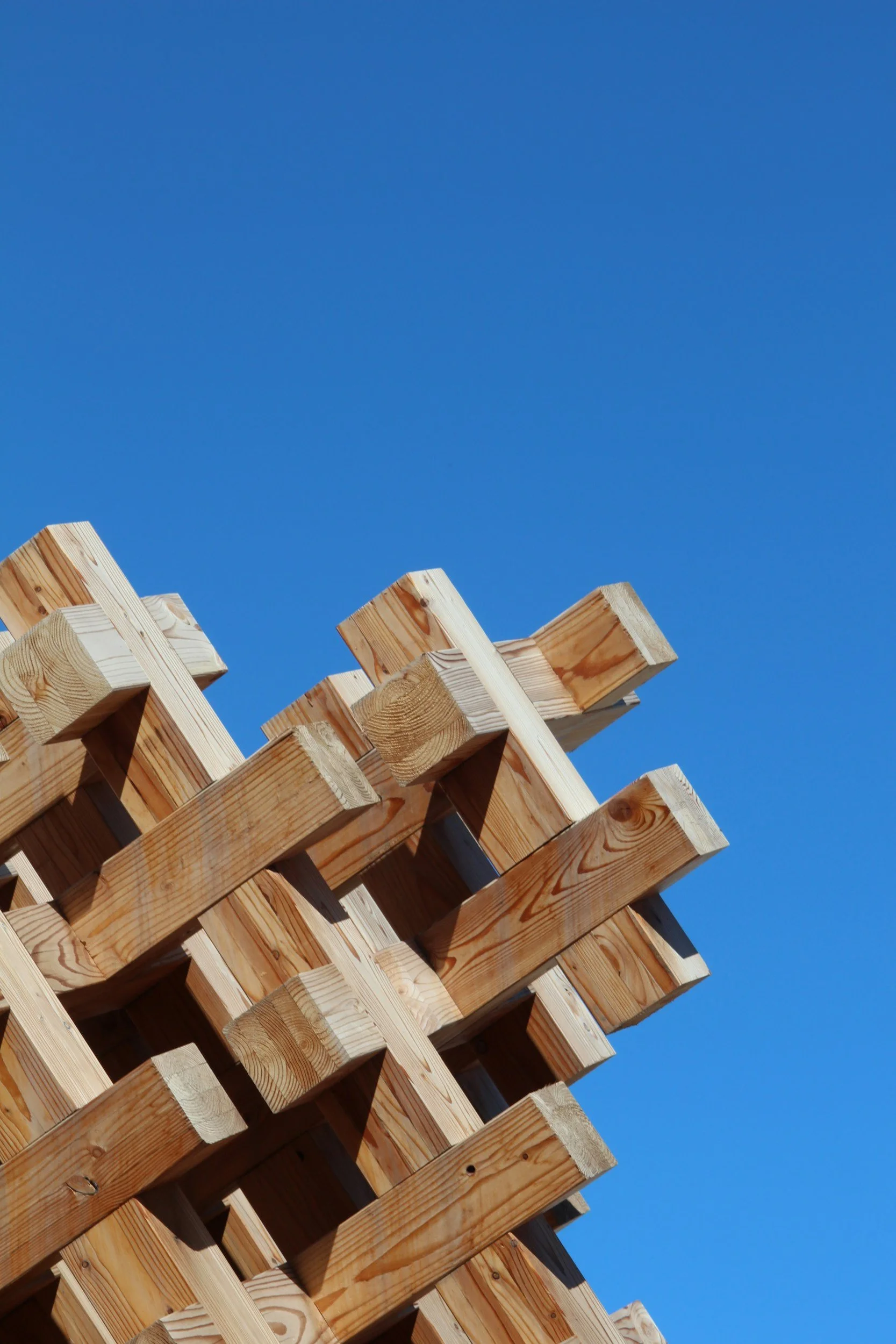 Close-up of a wooden pallet or structure against a clear blue sky.