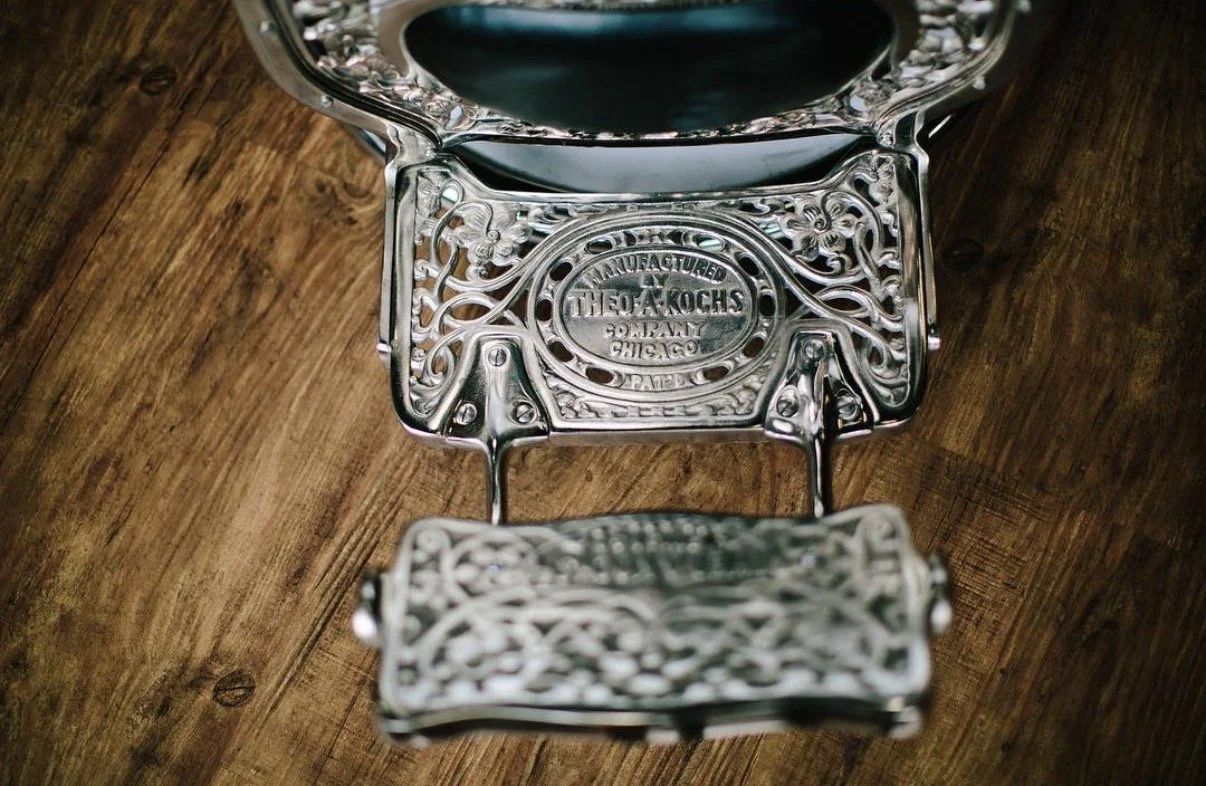 Close-up of an ornate silver vintage letter scale with a copper base, placed on a wooden surface.