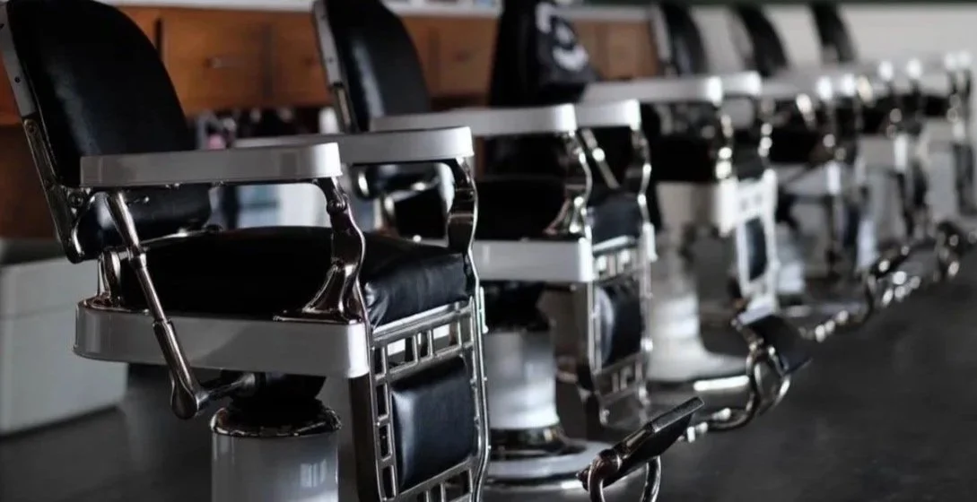Multiple empty barber chairs in a salon or barbershop.