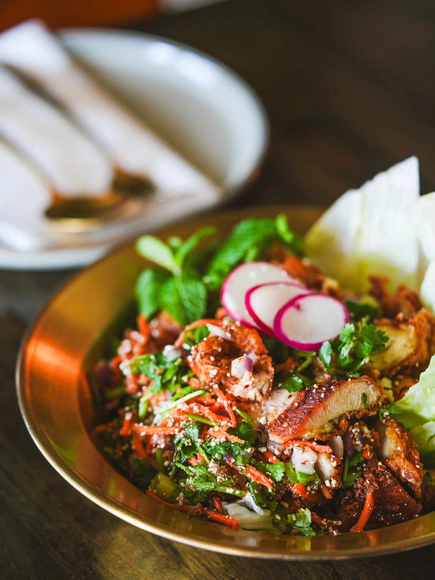 A plate of Asian-style salad with sliced radishes, cilantro, and lettuce with side of white rice.