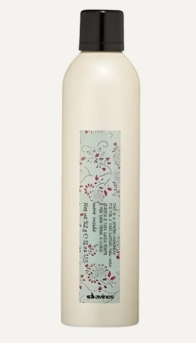 A white bottle with a black cap and a rectangular label that has decorative illustrations and text.