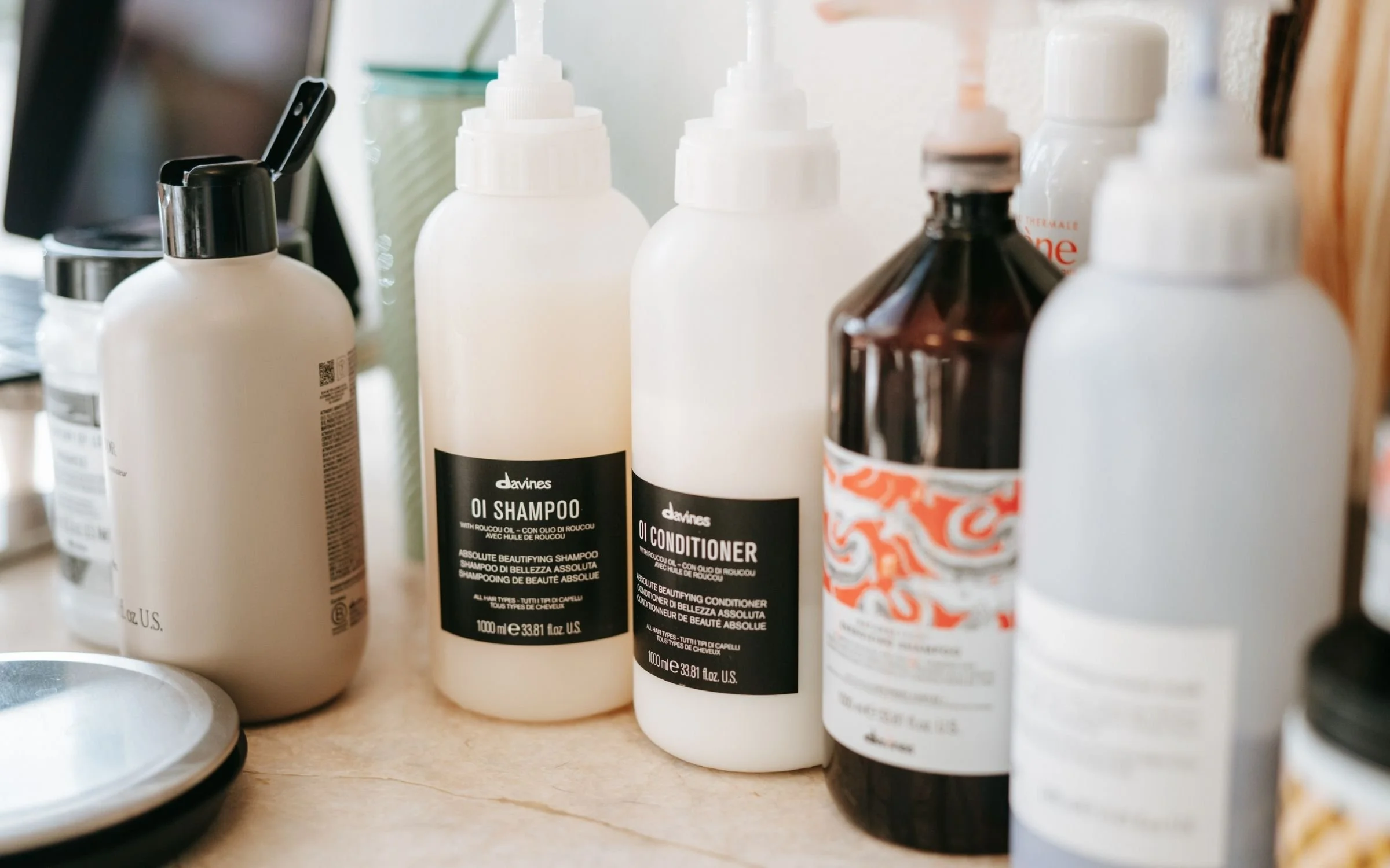 Various hair care bottles on a shelf, including shampoo and conditioner, with black, white, and brown labels.