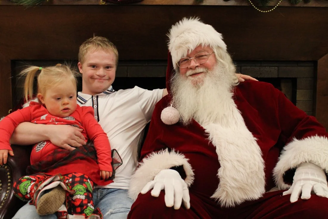 Three children sitting with Santa Claus in a festive setting.