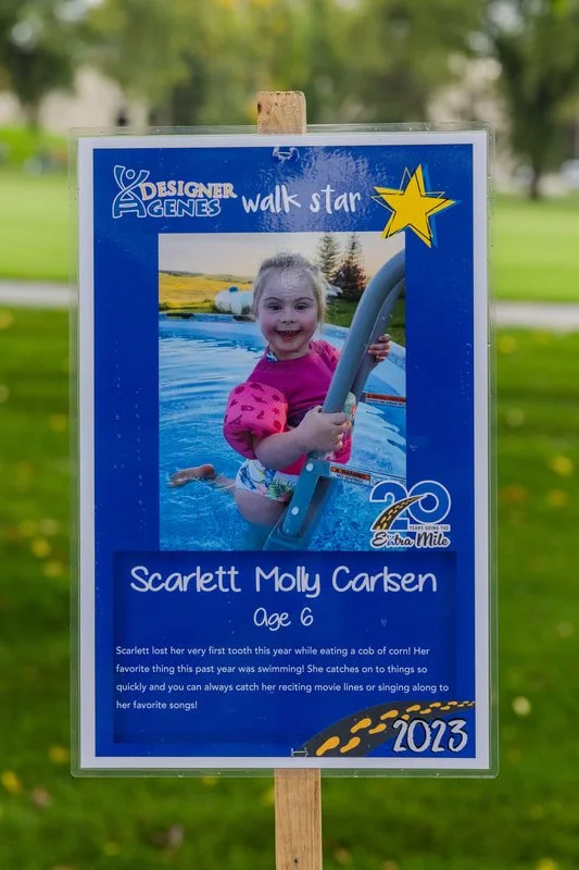 Sign featuring a photo of a young girl swimming in a pool, with text about her age, name, and a personal story, decorated with a yellow star and the year 2023.