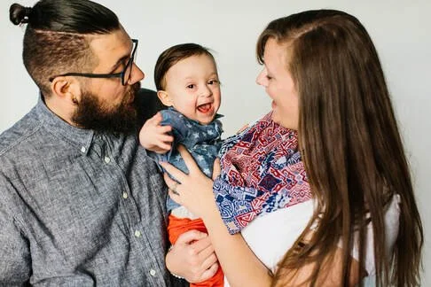 Family of three with a man, woman, and a smiling baby girl.