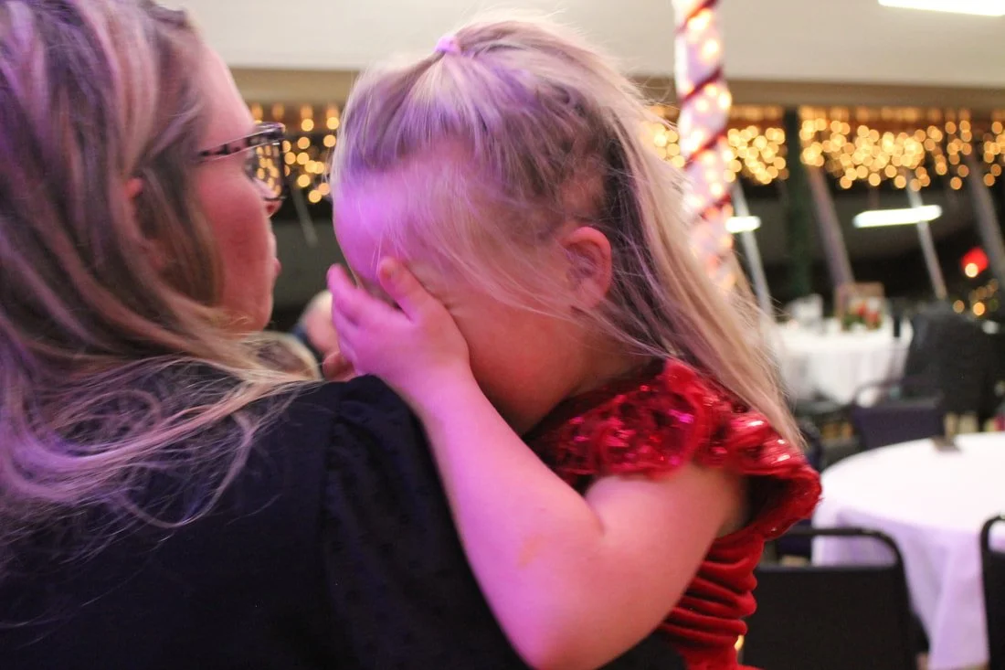 A woman holding a young girl who is crying or upset inside a decorated banquet hall or restaurant.