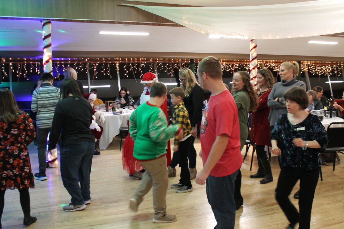 People dancing and socializing at a holiday party with Christmas decorations and twinkling lights.