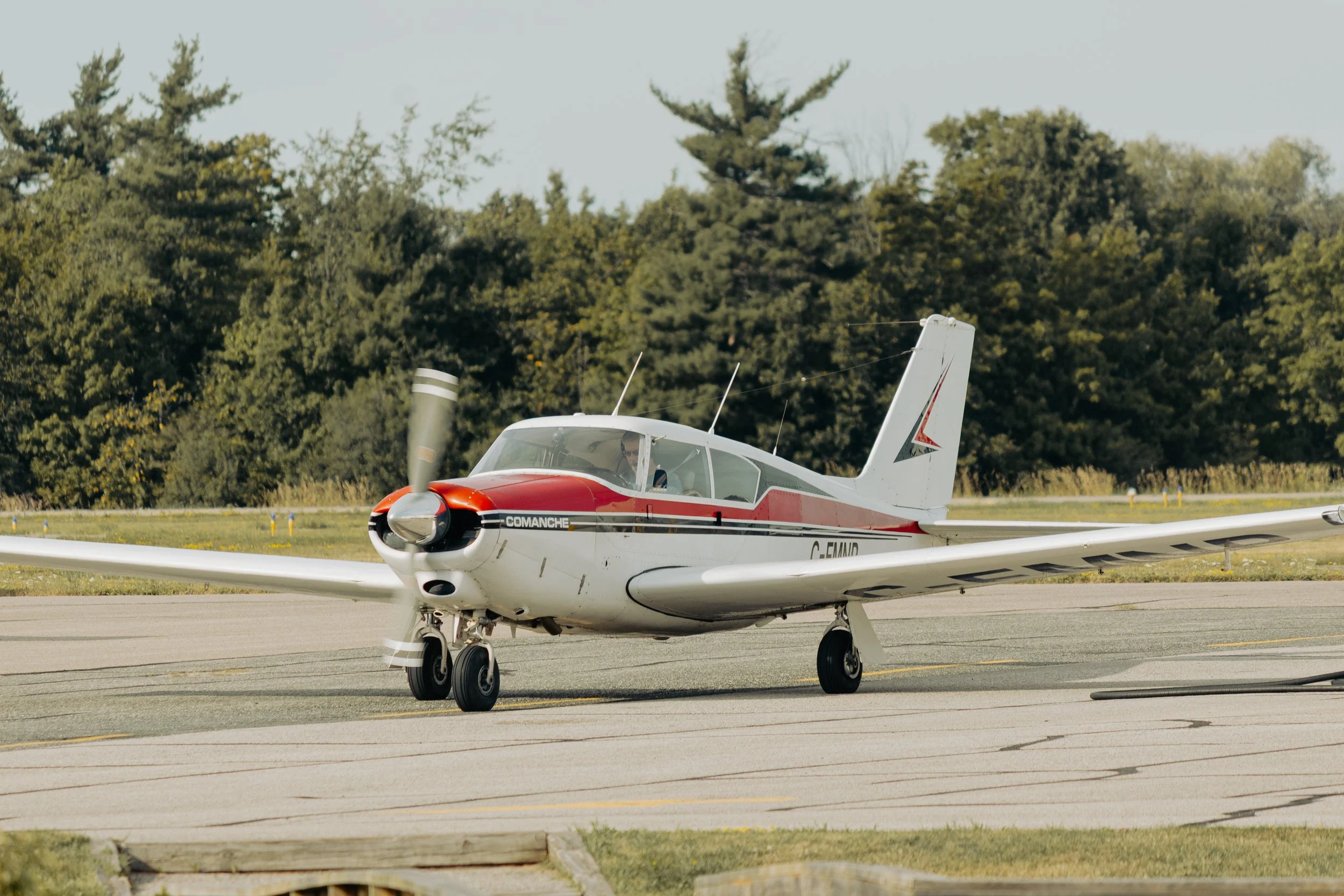Small airplane on an airport tarmac with trees in the background.