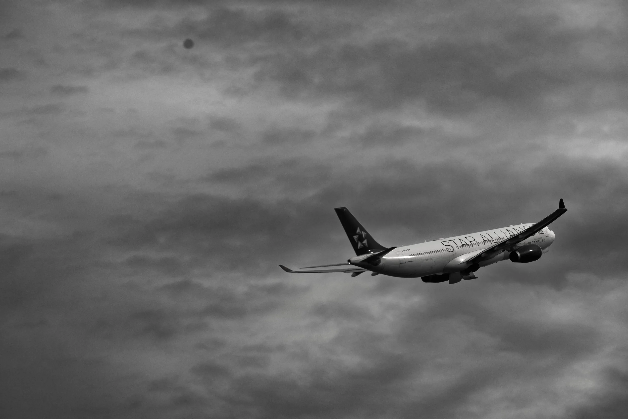 A commercial airplane flying in a cloudy sky with the word 'STAR ALLIANCE' on its side and a star design on its tail.