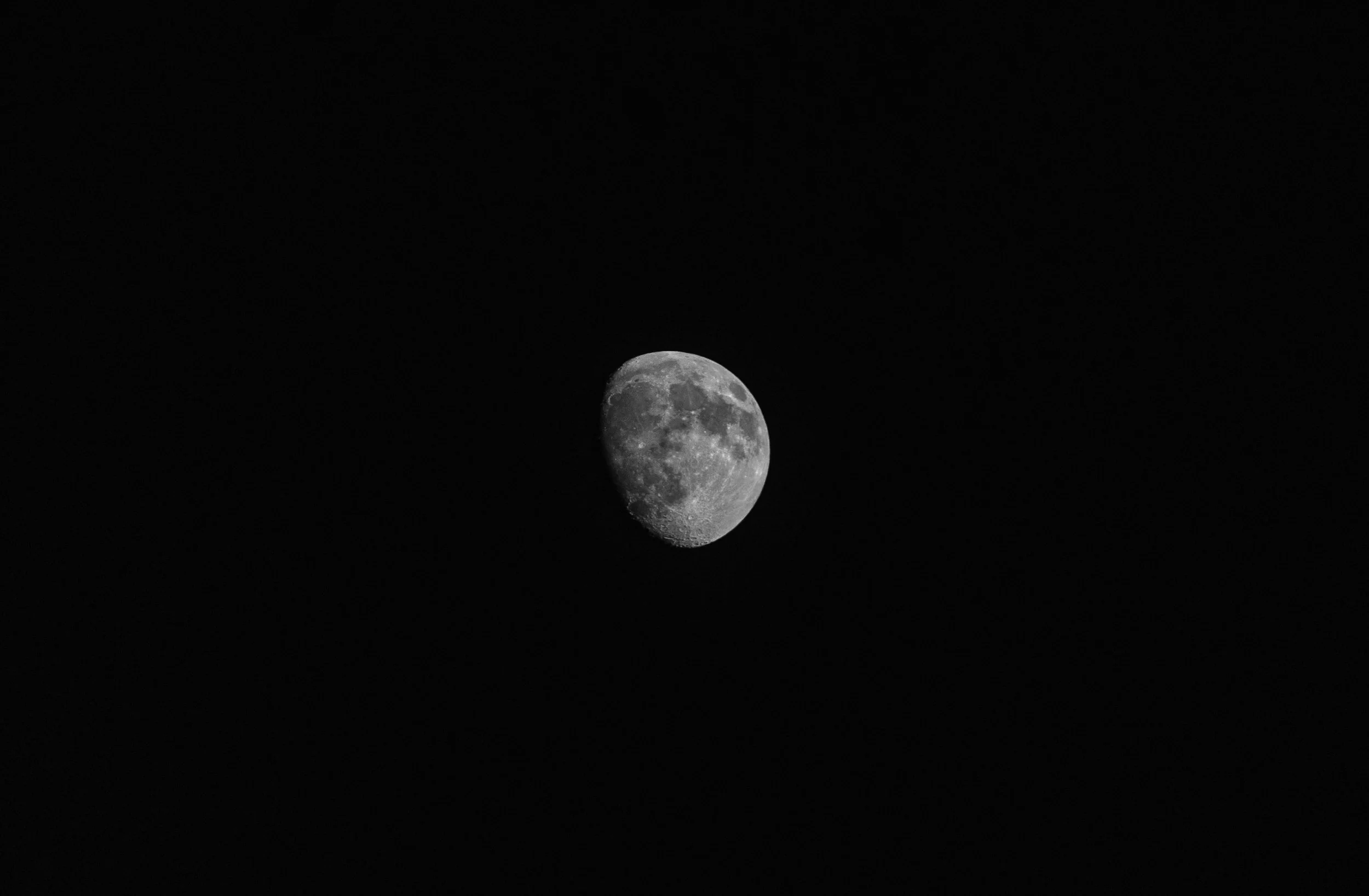 The moon shows a waxing gibbous phase with visible craters against a dark night sky.