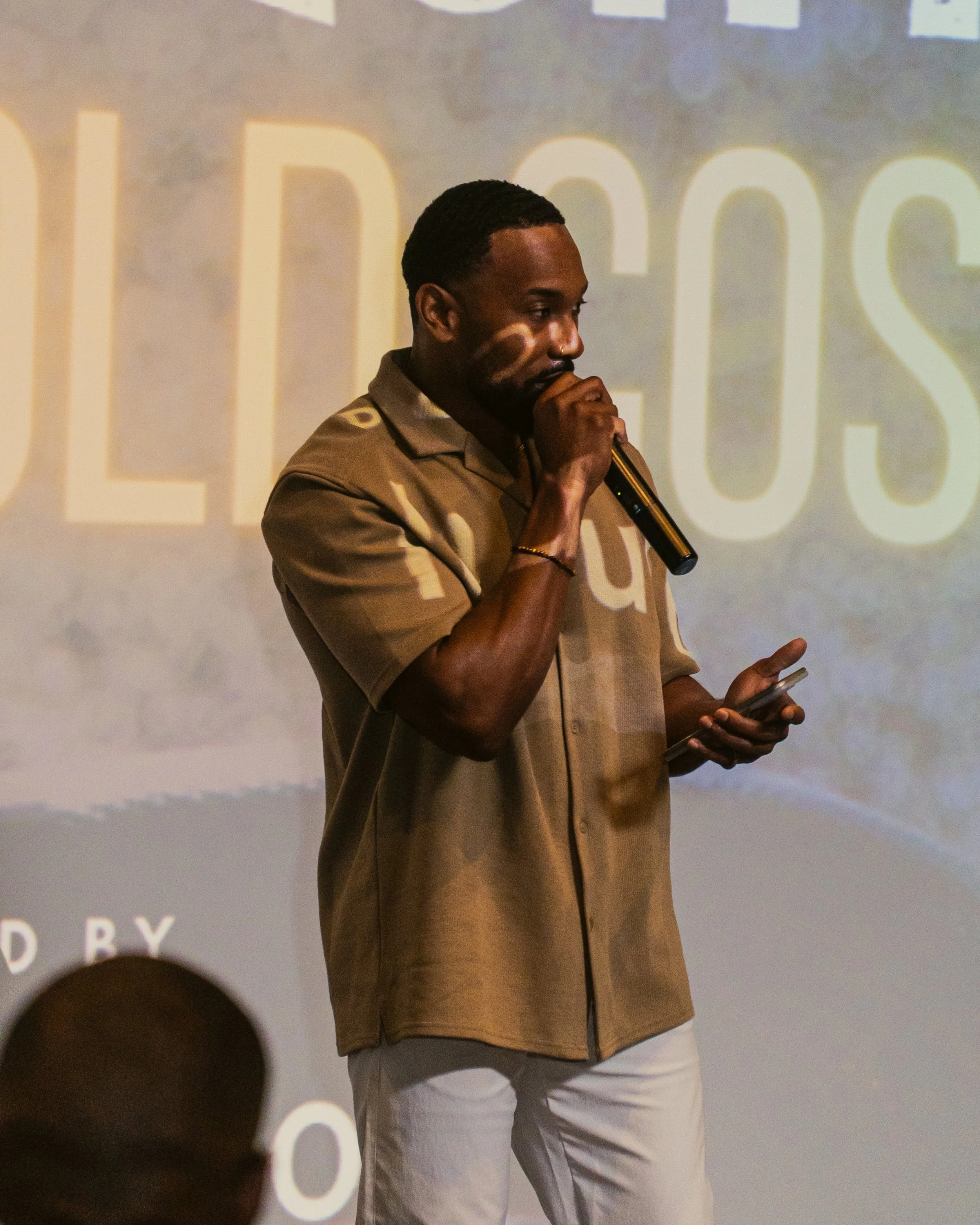 Rob Owens, co-producer of Rogue Elephants, speaks to an audience while holding a microphone during a film screening event.
