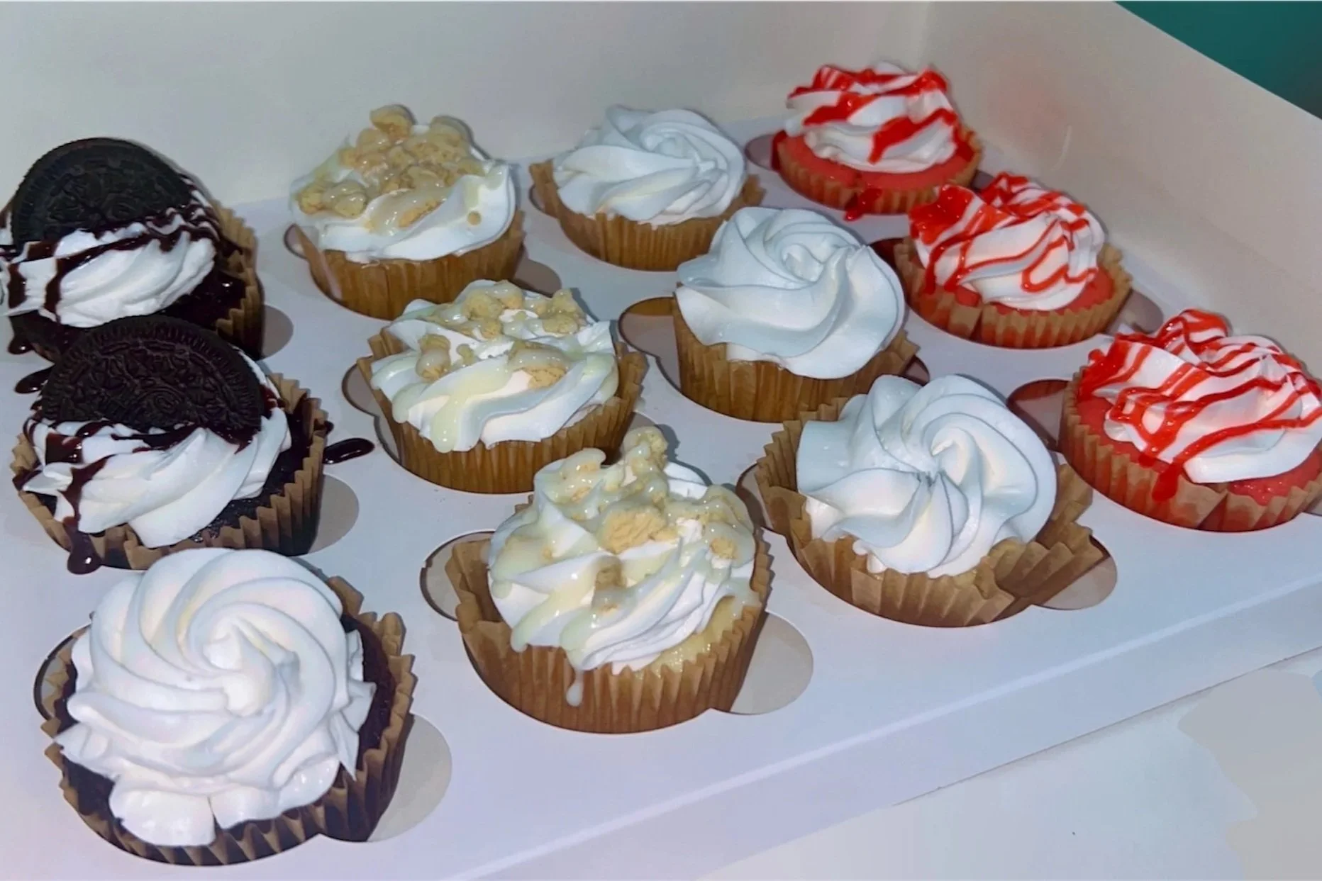A tray of assorted cupcakes with various toppings and icing designs.